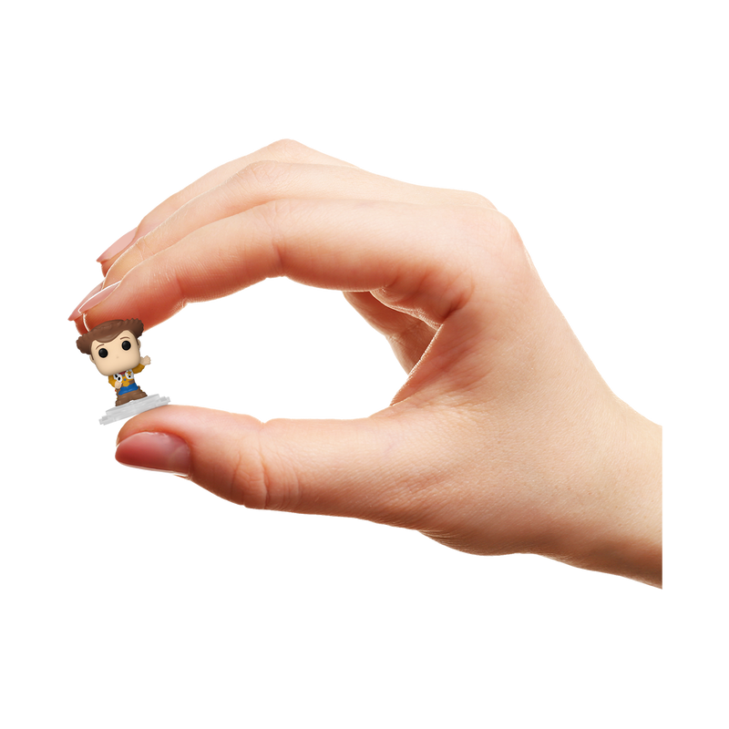 Una mano sostiene una pequeña figura de Woody sobre fondo negro.