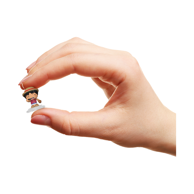 Una mano sostiene una pequeña figura de anime con sombrero de paja sobre fondo negro.