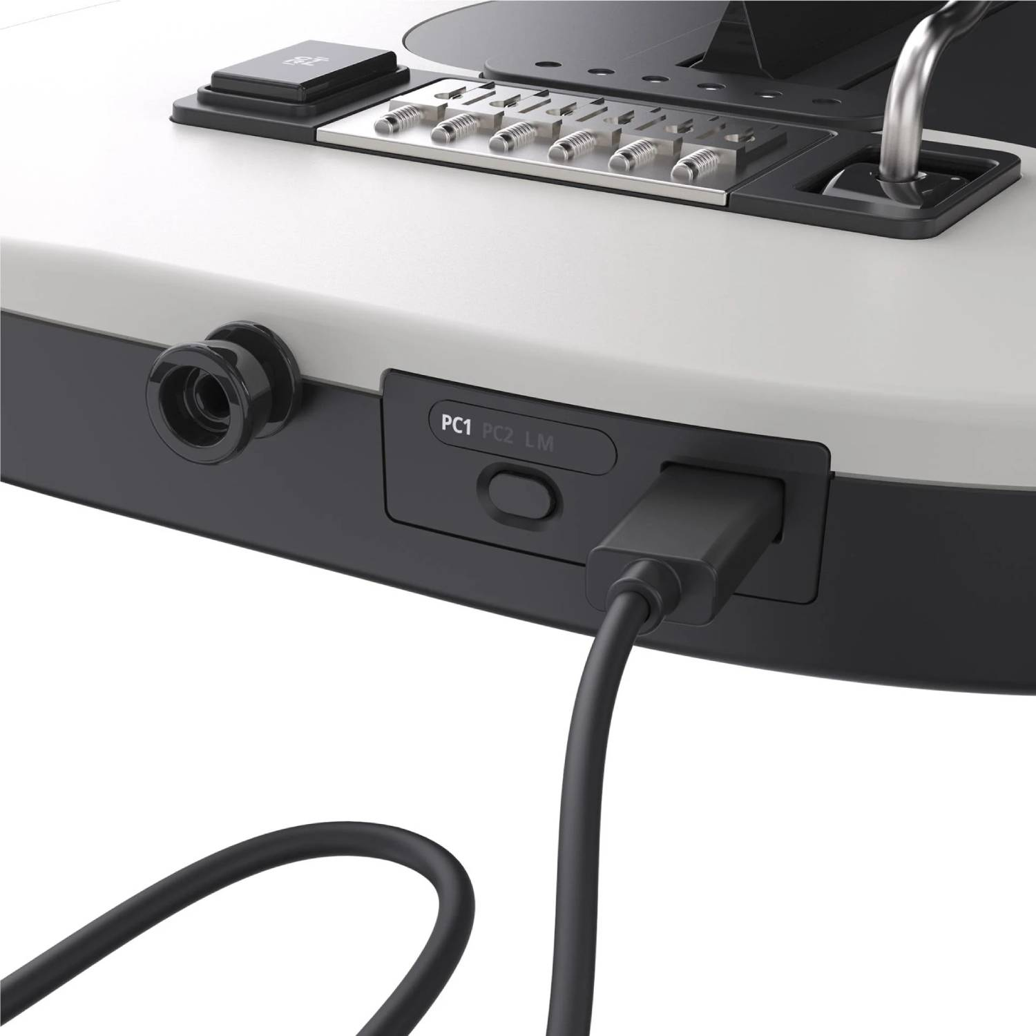 Primer plano de una consola blanca y negra con botones, puertos y un cable negro conectado.