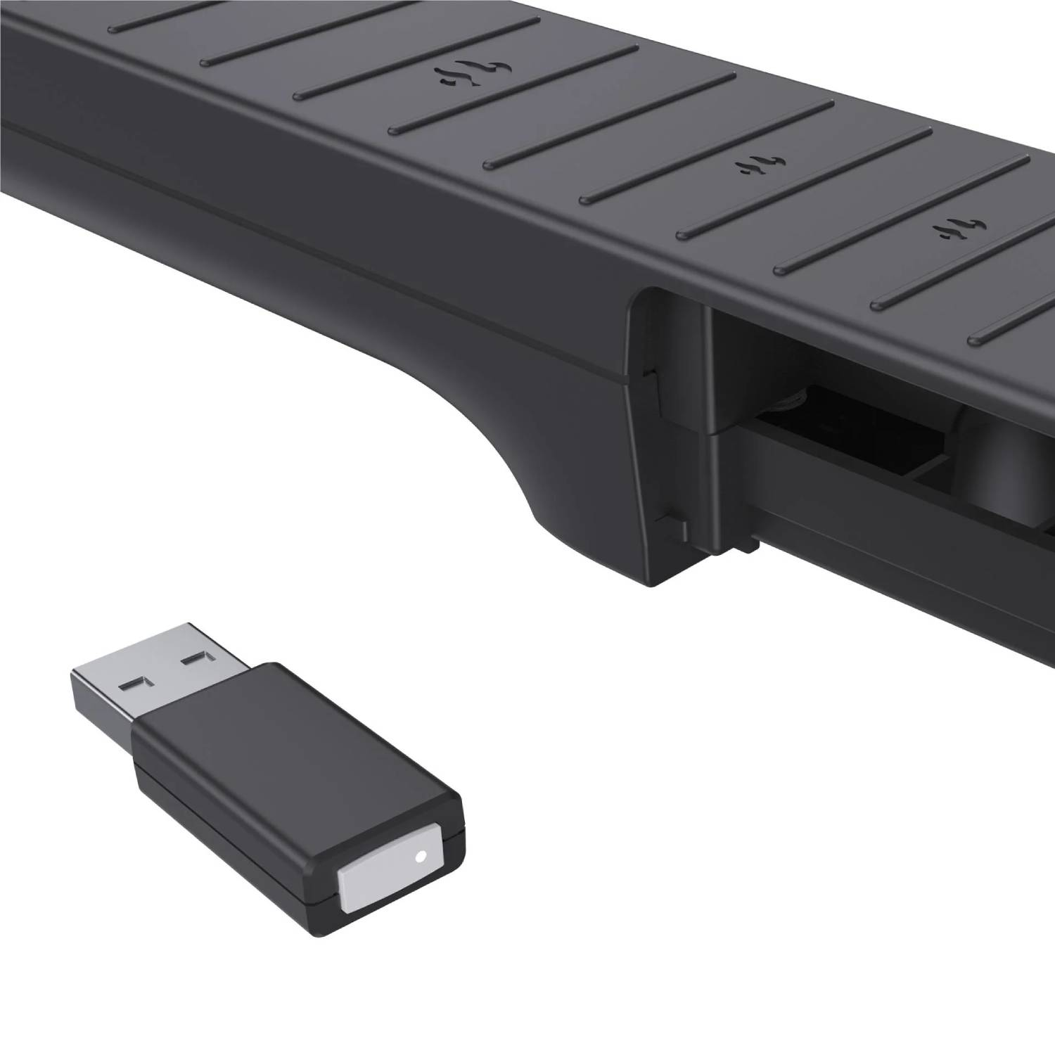 Un adaptador USB negro sobre una superficie blanca junto a un dispositivo negro más grande con la parte superior texturizada.