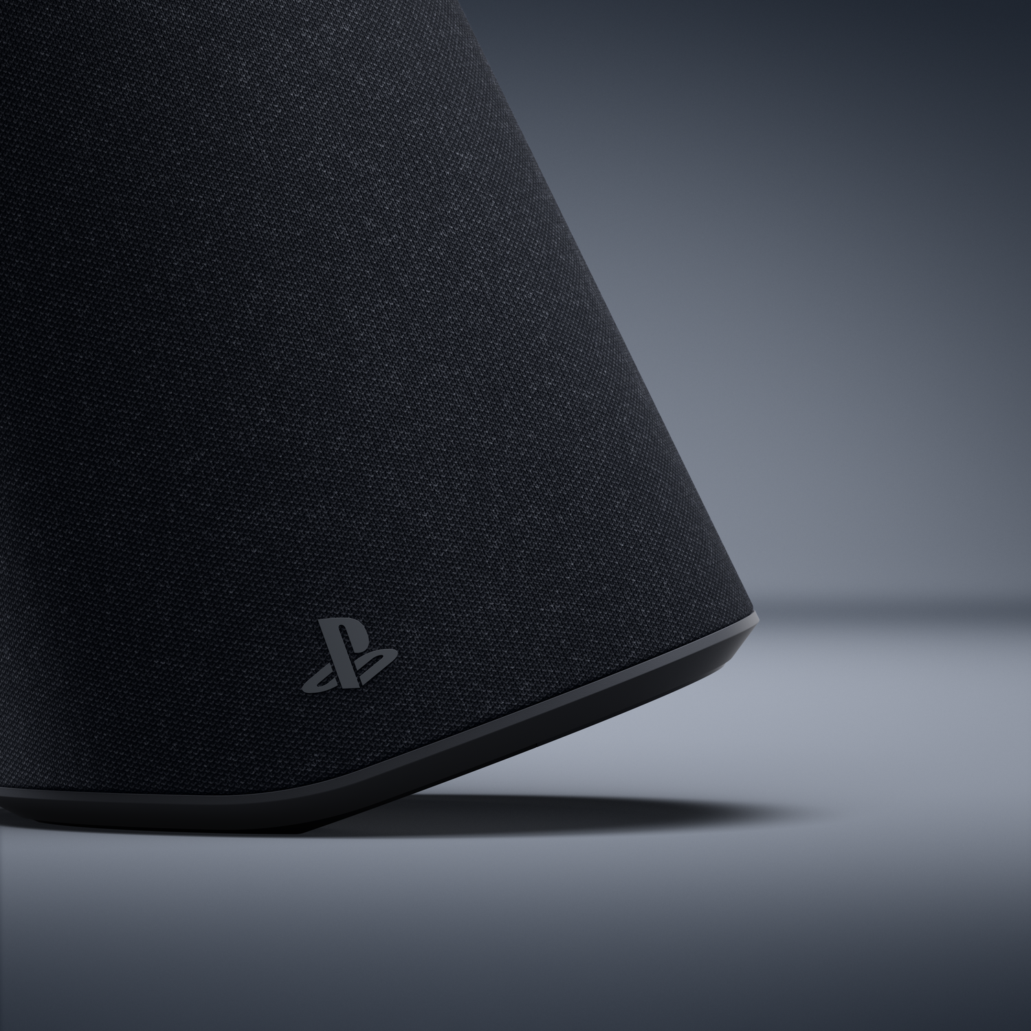 Gros plan d'un objet en tissu noir avec le logo PlayStation sur fond gris foncé.