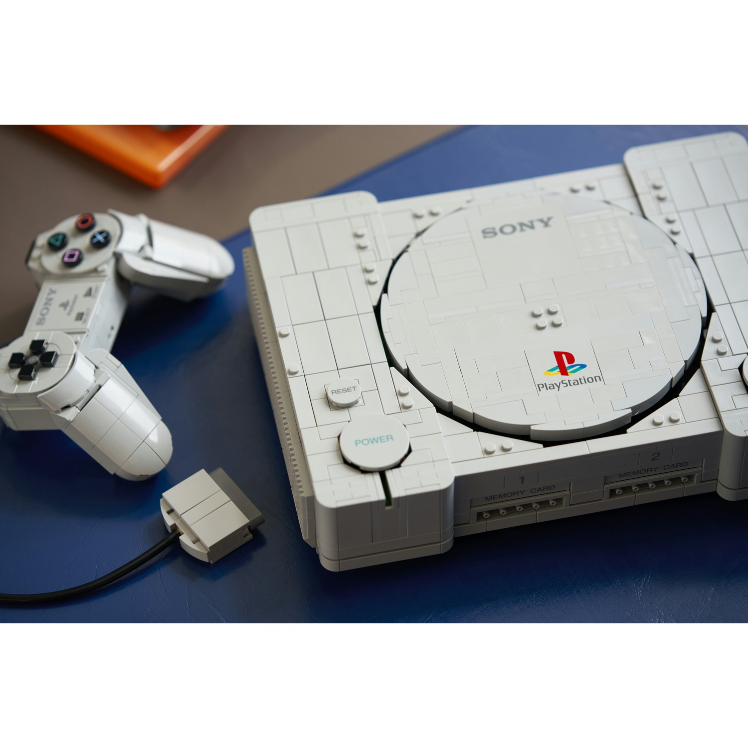 Una console PlayStation e un controller in Lego su un tavolo blu.