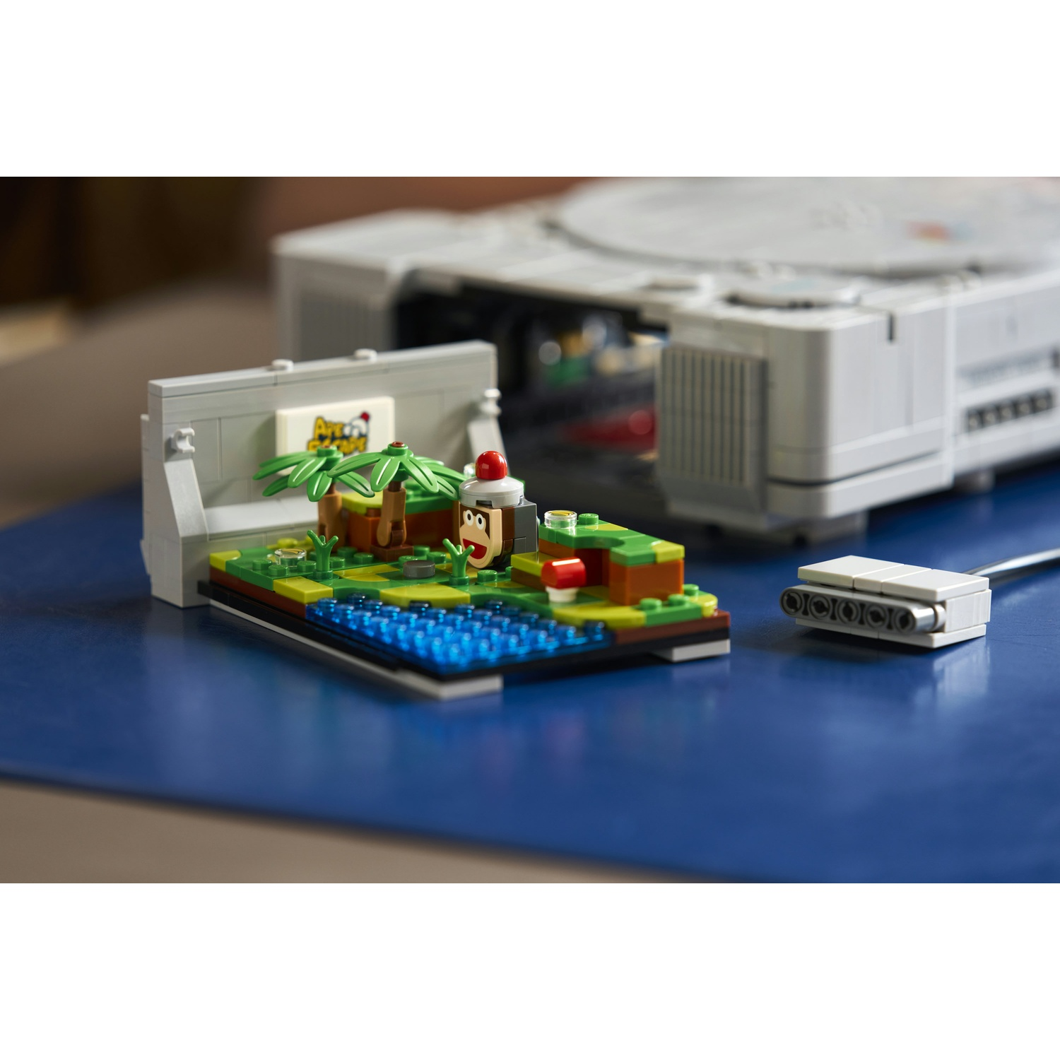 Un modello di PlayStation Lego con un piccolo diorama davanti su una superficie blu.