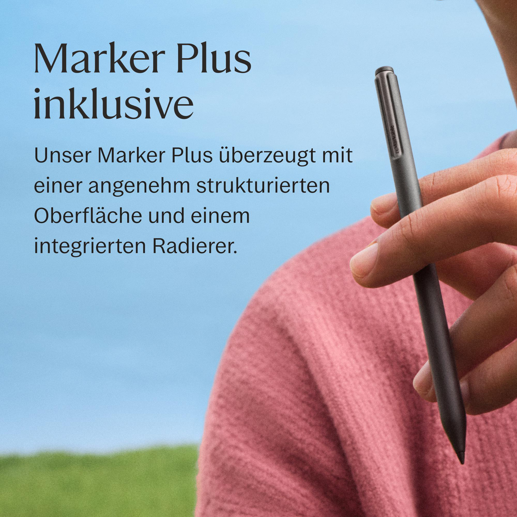 Eine Person hält einen grauen Stift vor einem blauen Himmel und grüner Wiese. Text auf dem Bild.
