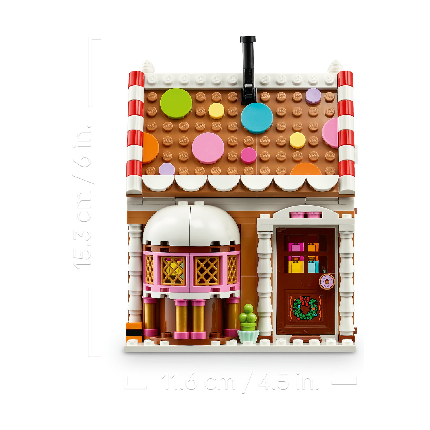 Una colorata casa di pan di zenzero Lego con tetto marrone, caramelle, porta decorata e indicatori di misura.