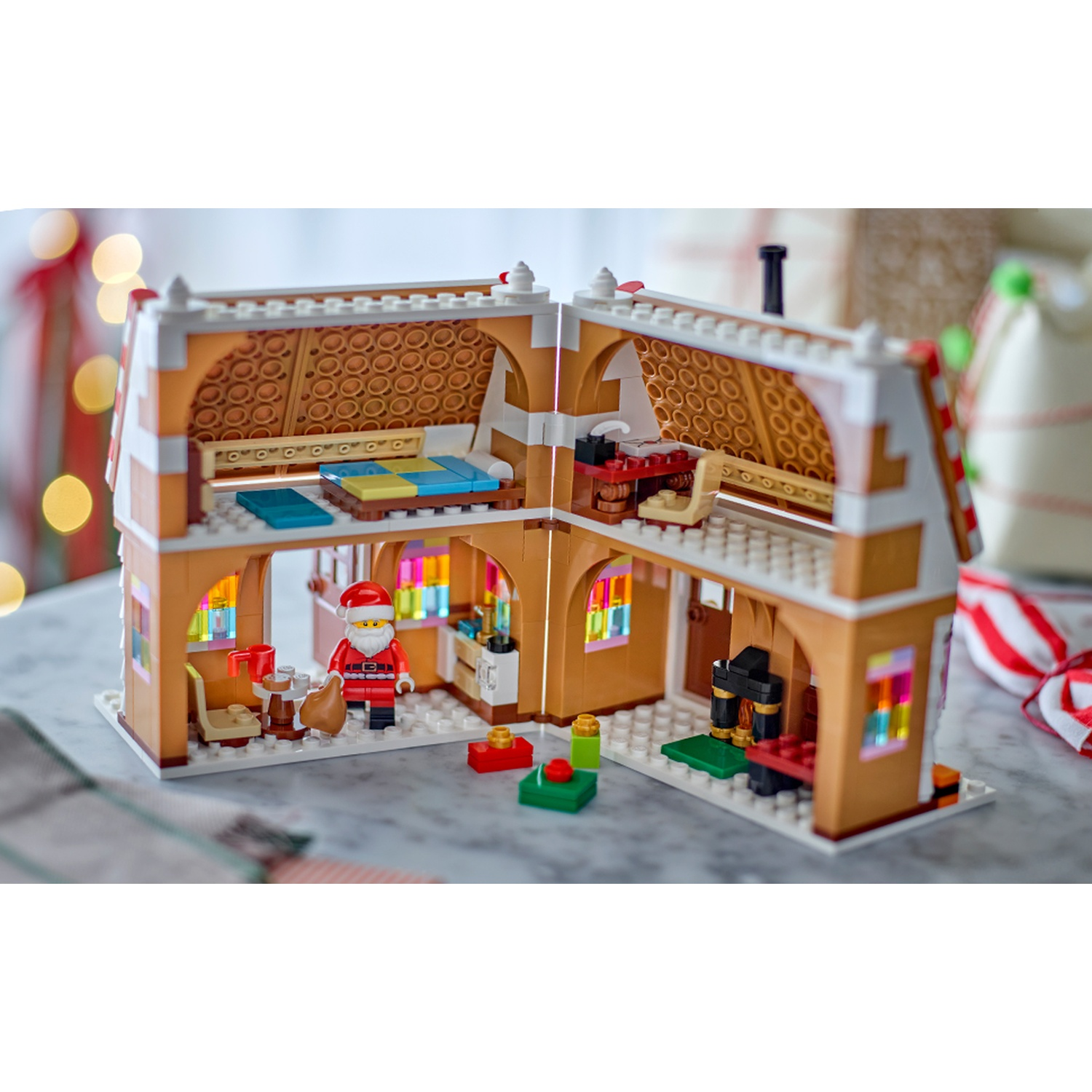 Una casa di marzapane Lego a due piani, una minifigura di Babbo Natale, un camino e decorazioni natalizie.