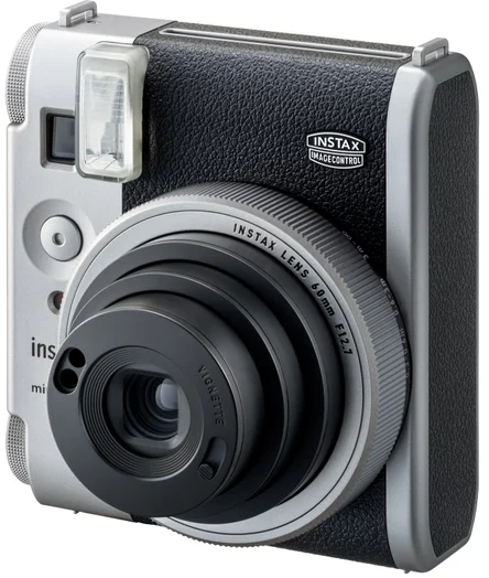 Fekete-ezüst Fujifilm Instax azonnali kamera nagy behúzható lencsével és beépített vakuval fehér háttér előtt.