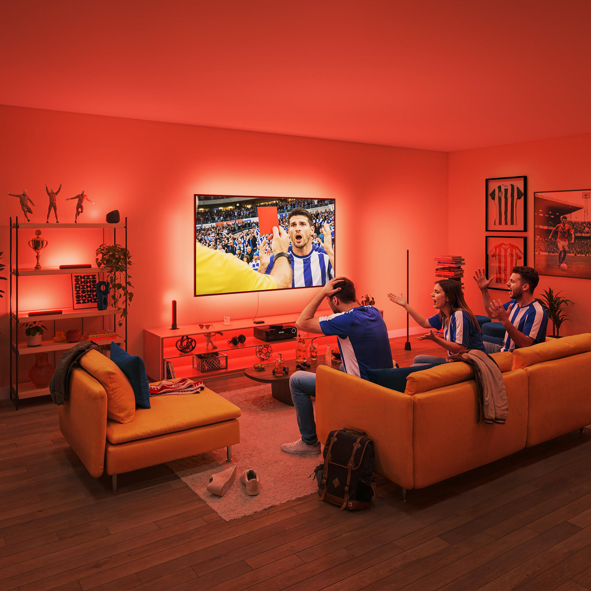Drei Fans schauen Rote Karte auf beleuchtetem Fernseher im roten Wohnzimmer.