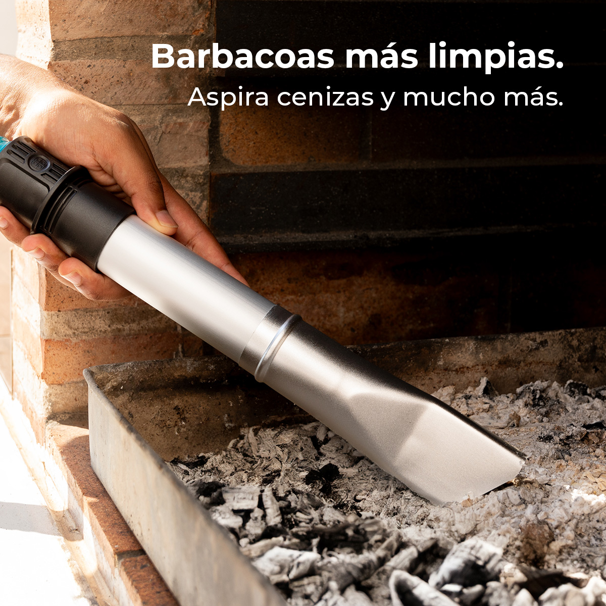 Una mano usa una aspiradora para quitar cenizas de la bandeja de una barbacoa.