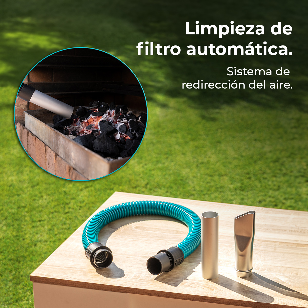 Manguera de aspiradora turquesa y dos accesorios metálicos en una mesa de madera, con una parrilla encendida de fondo.
