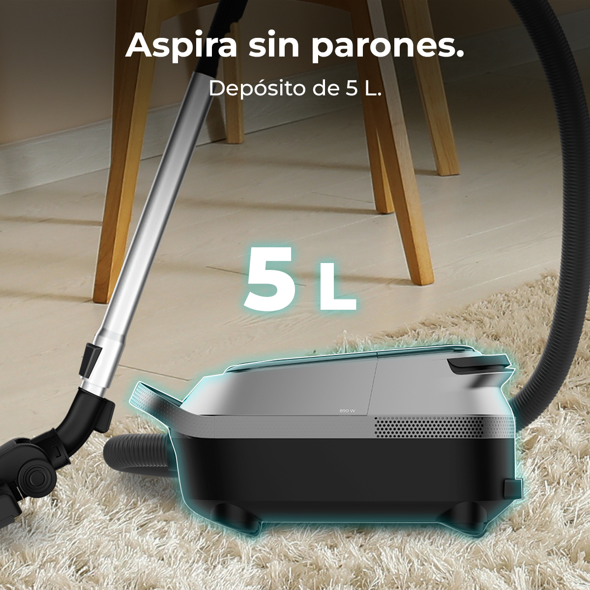 Aspiradora gris sobre alfombra clara cerca de muebles de madera con texto sobre depósito de 5L.