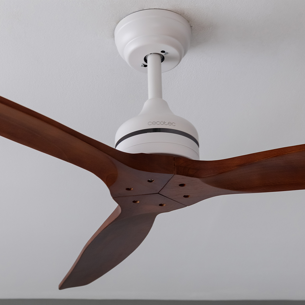 Un ventilador de techo blanco con tres aspas de madera marrón montado en un techo blanco.