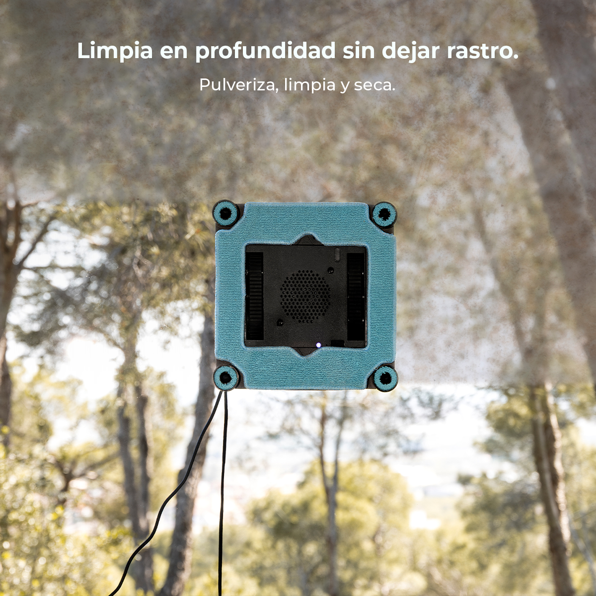 Un robot limpiador de ventanas azul limpia un cristal con un fondo de bosque.