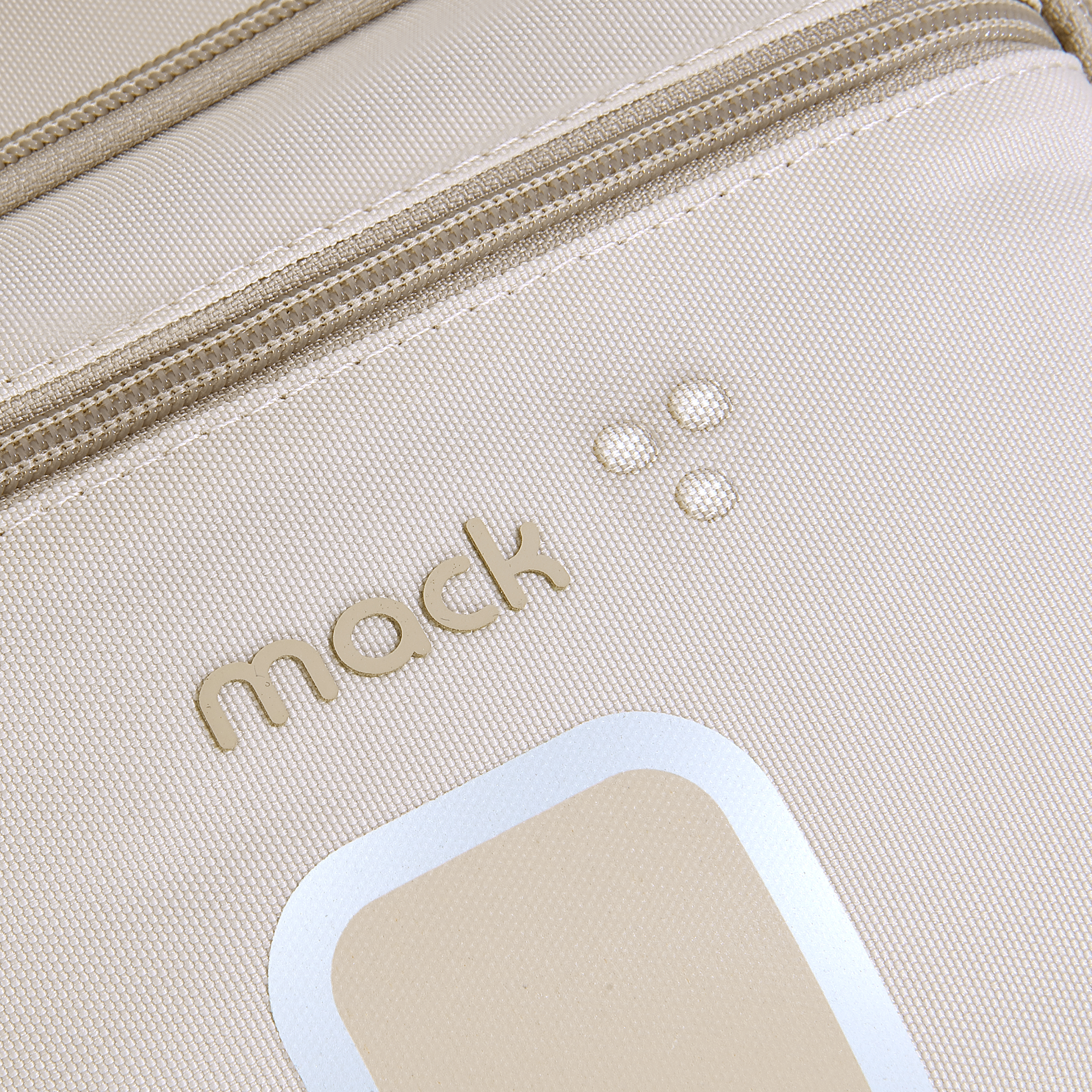 Fermuarlı, 'mack' yazılı ve açık renkli amblemli bej rengi bir çantanın yakın çekimi.