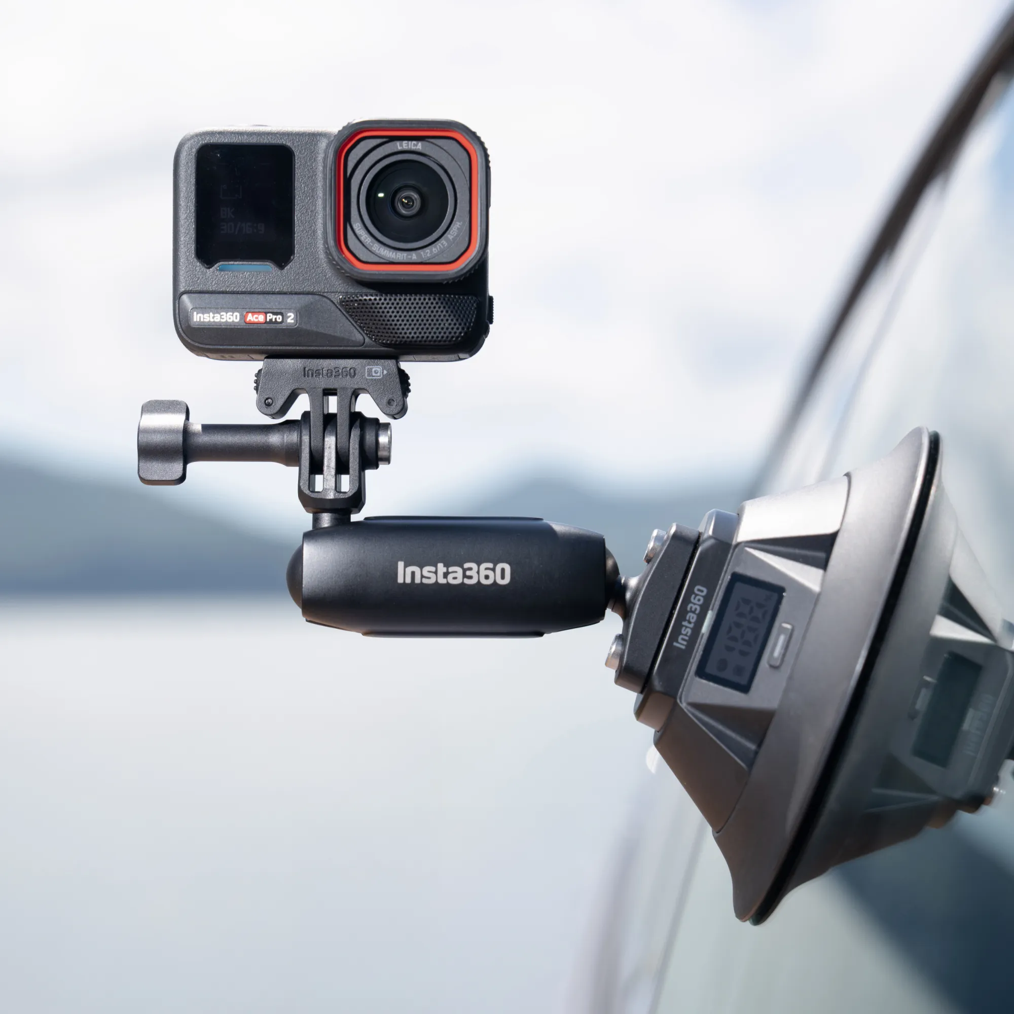 Egy Insta360 kamera egy autó ablakára van rögzítve tapadókorongos tartóval, elmosódott kültéri háttérrel.