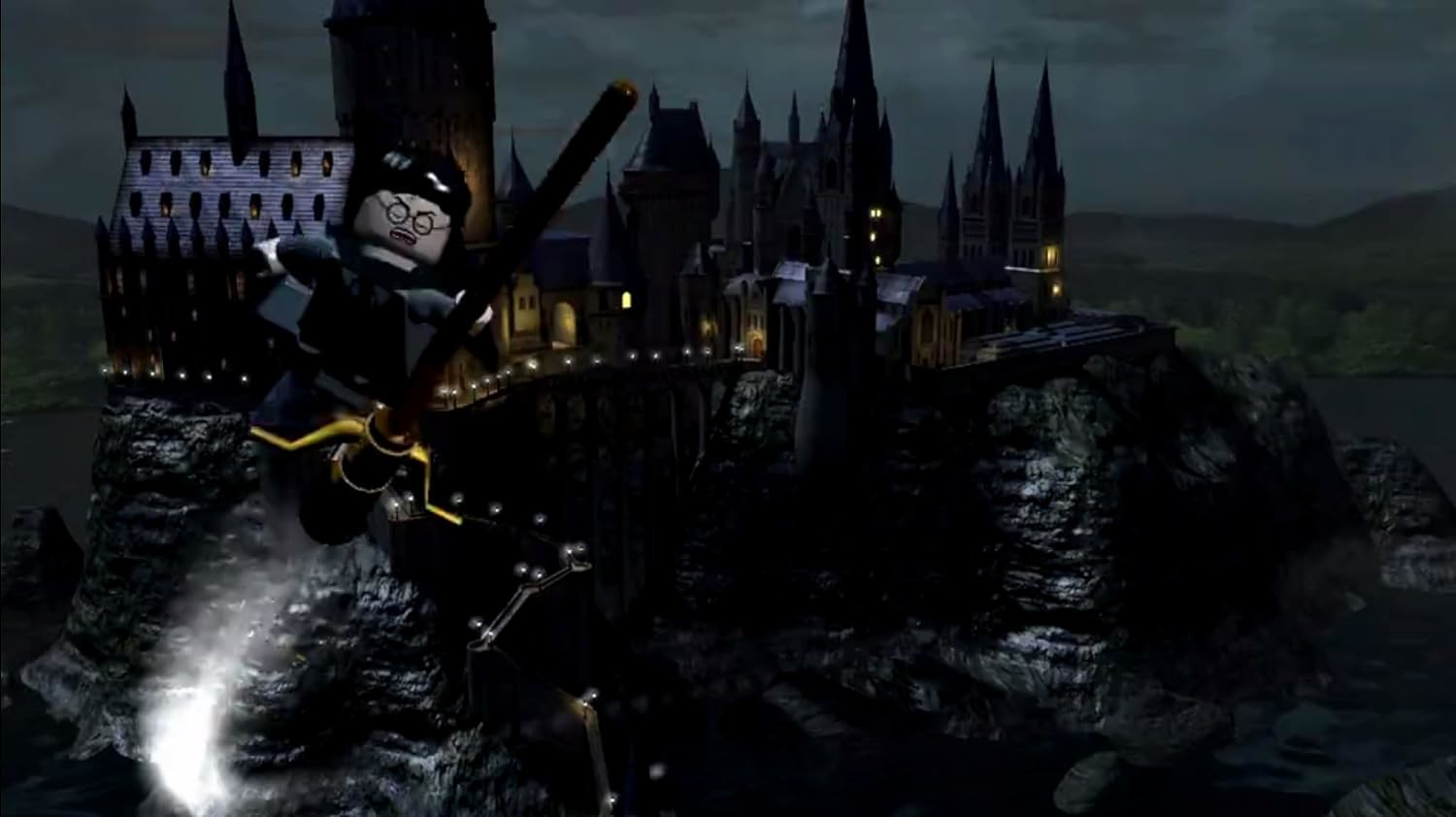 Une figurine Lego vole sur un balai la nuit devant un château sombre.