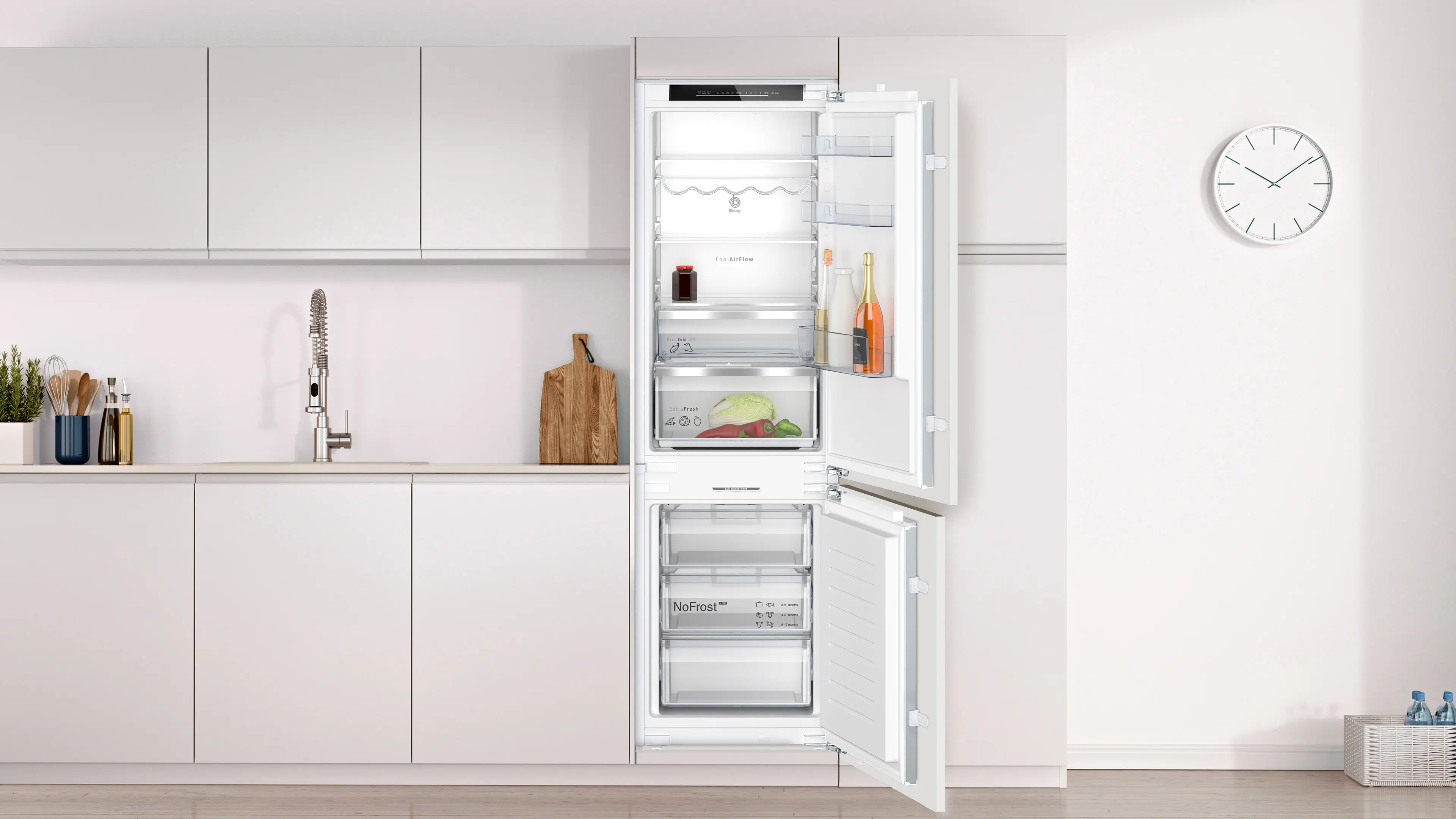 Moderna cocina blanca con frigorífico empotrado con puertas abiertas, fregadero, tabla y reloj.
