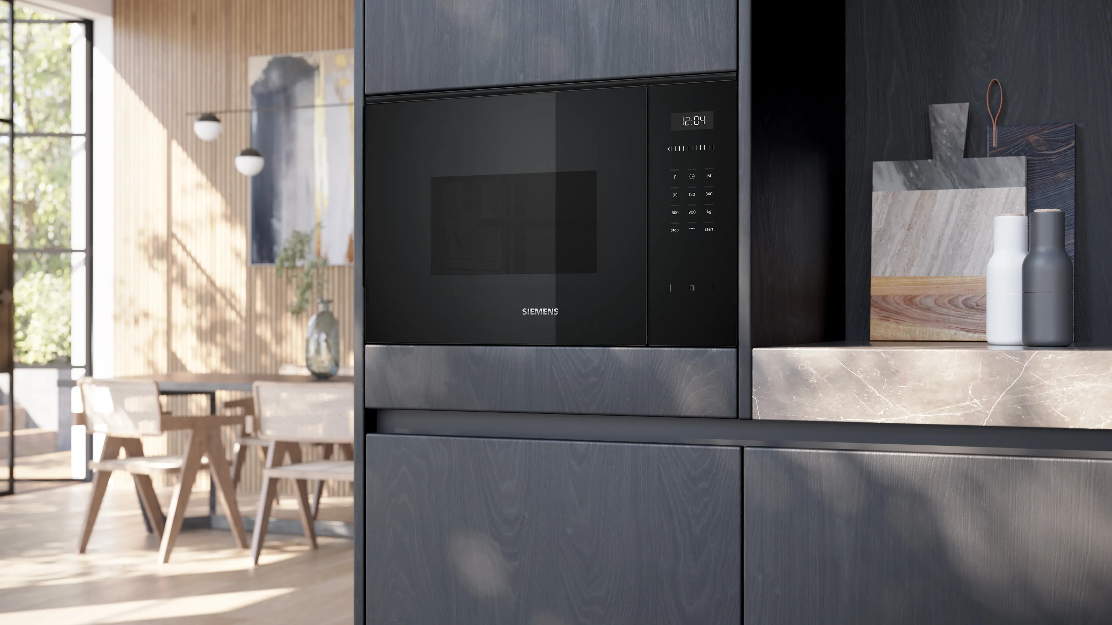 Un microondas empotrable Siemens negro en muebles de cocina oscuros con tablas de cortar en la encimera.