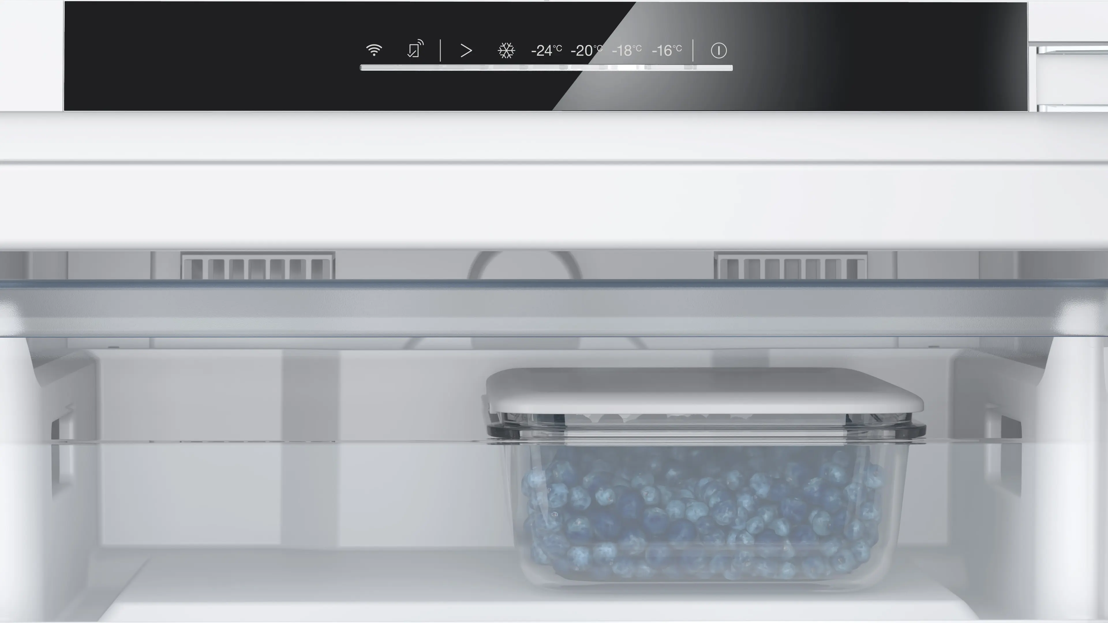 Interior de un refrigerador blanco con panel digital y un recipiente lleno de arándanos frescos.