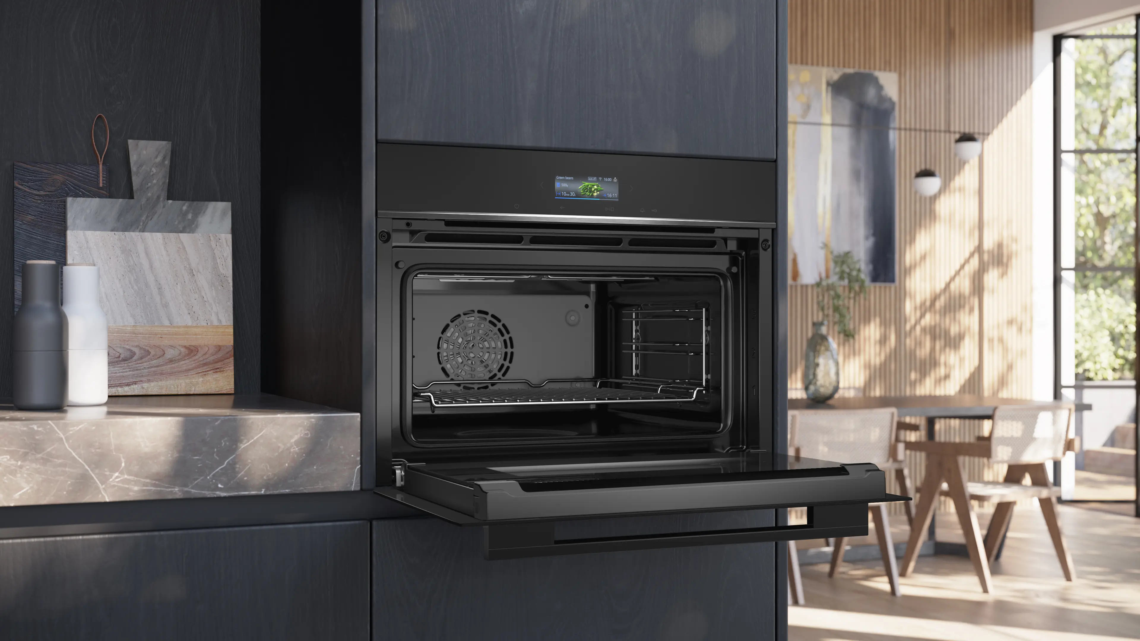 Horno empotrable negro abierto en una cocina moderna con pared de madera y comedor al fondo.