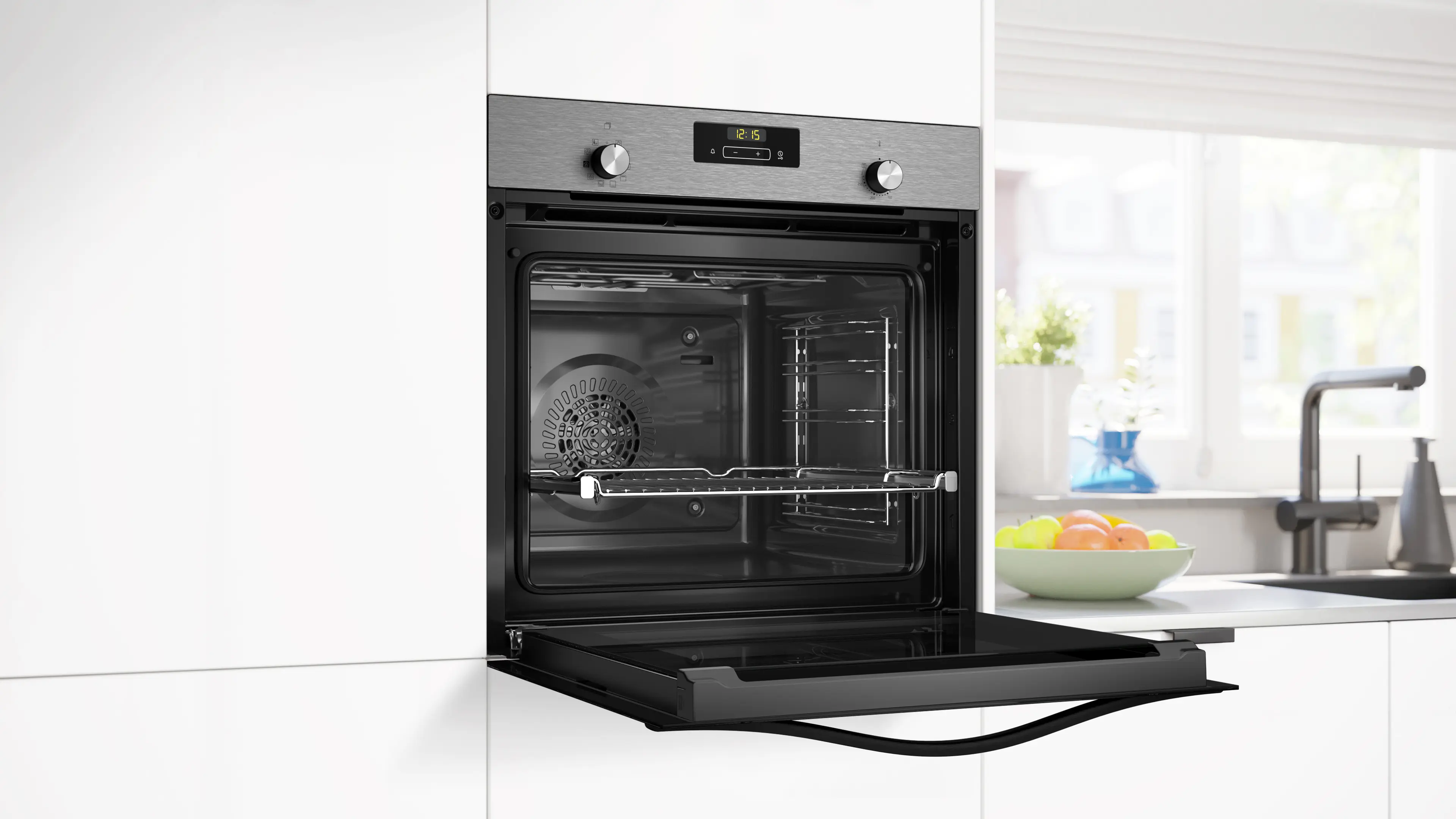 Horno empotrable de acero inoxidable con puerta abierta en cocina blanca.