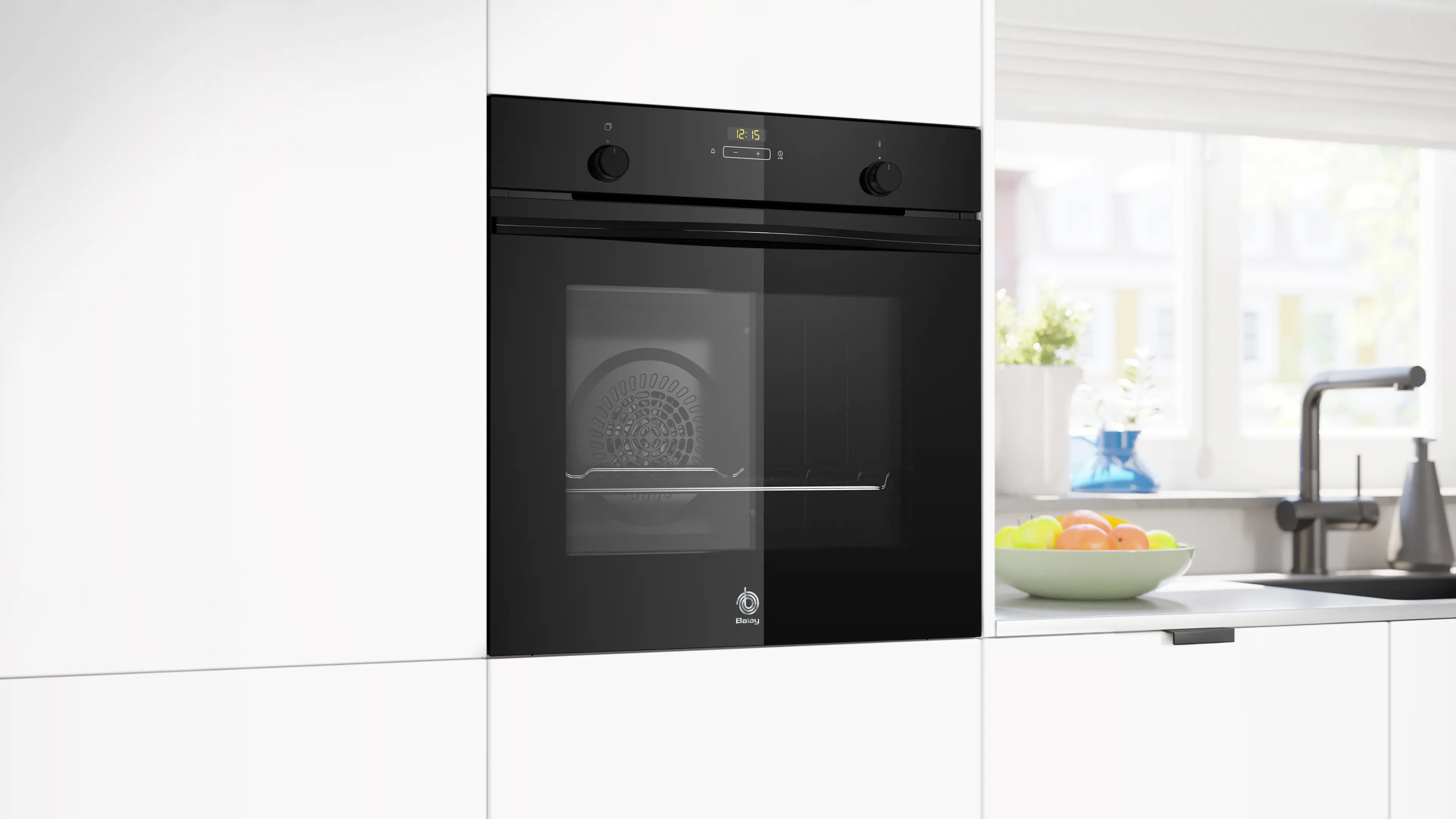 Moderno horno empotrado negro en cocina luminosa con frutero y fregadero al fondo.