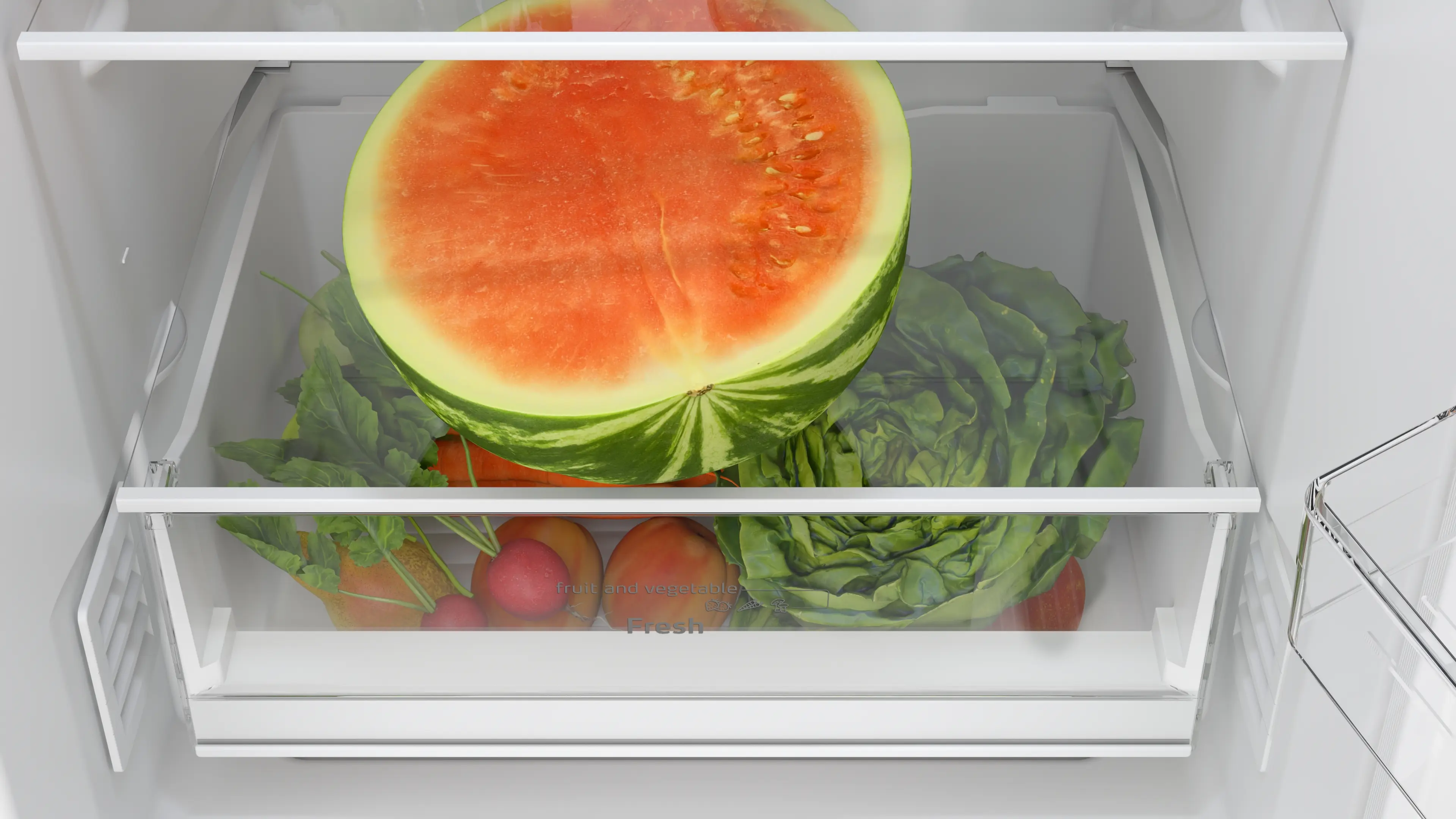 Cajón de verduras de refrigerador abierto con media sandía, lechuga y rábanos.