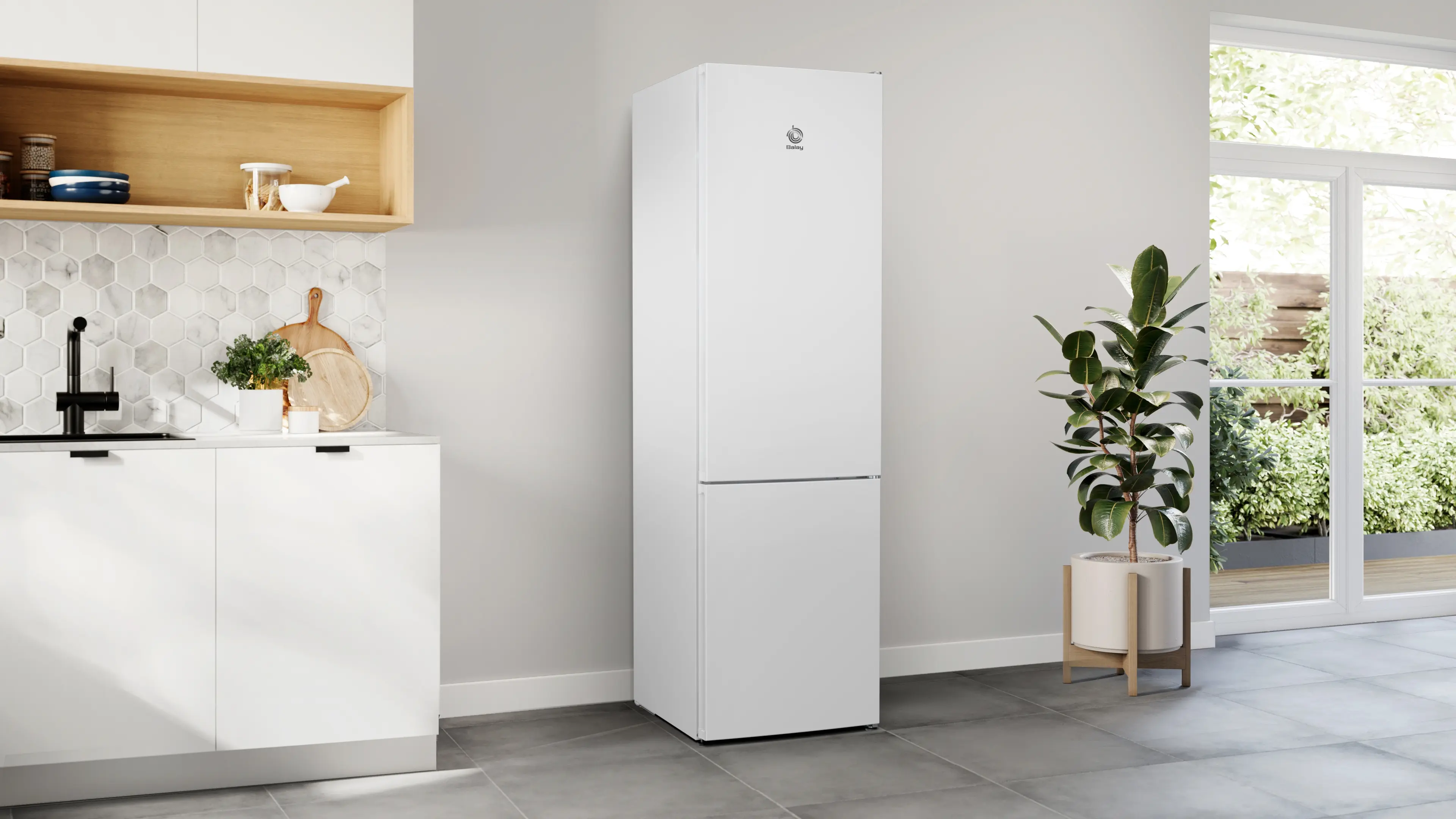 Un refrigerador blanco se encuentra en una cocina moderna con paredes gris claro, muebles blancos y una planta alta.