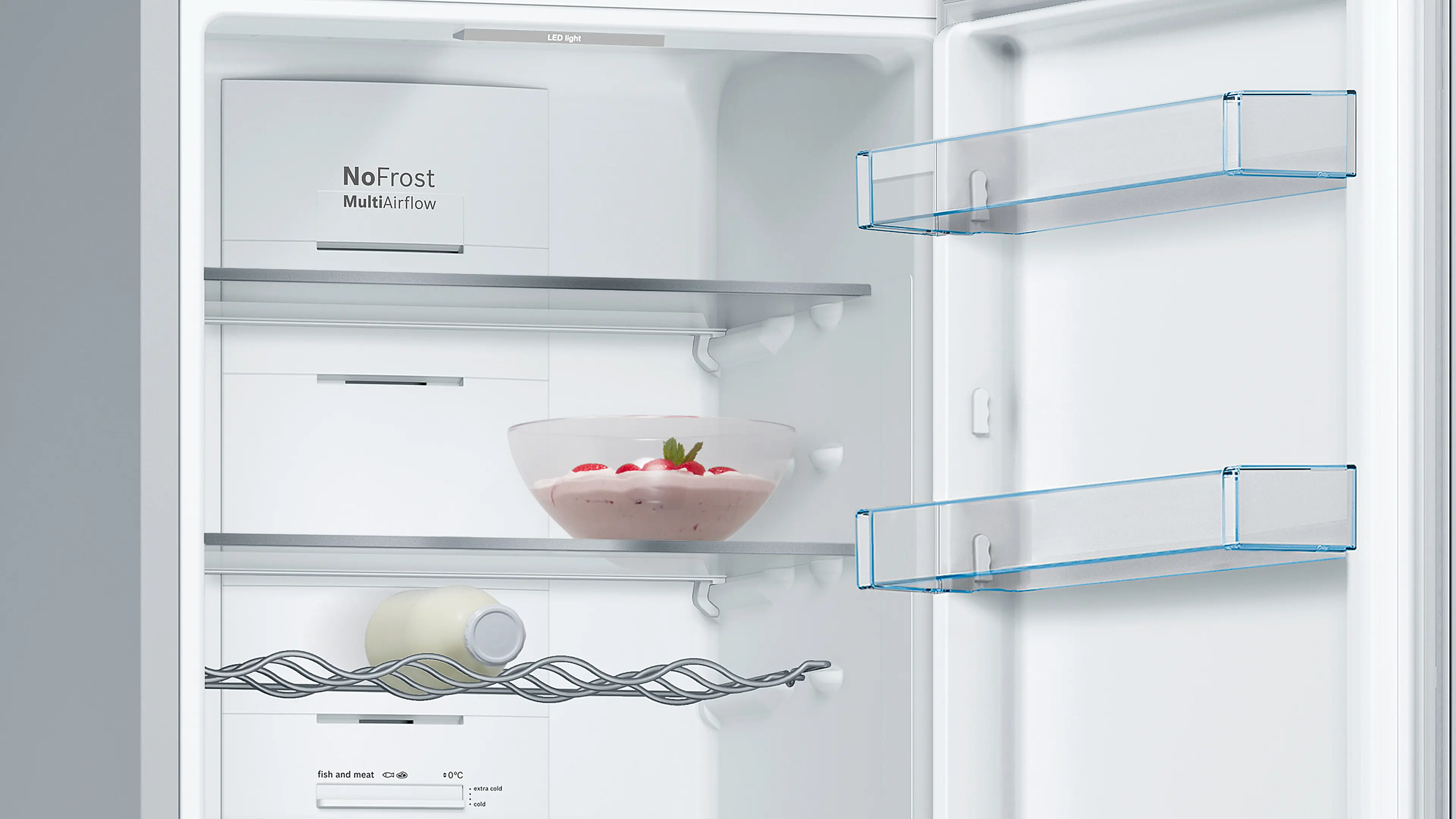 Vista interior de un refrigerador blanco abierto con estantes, una botella en rejilla y un bol con postre.