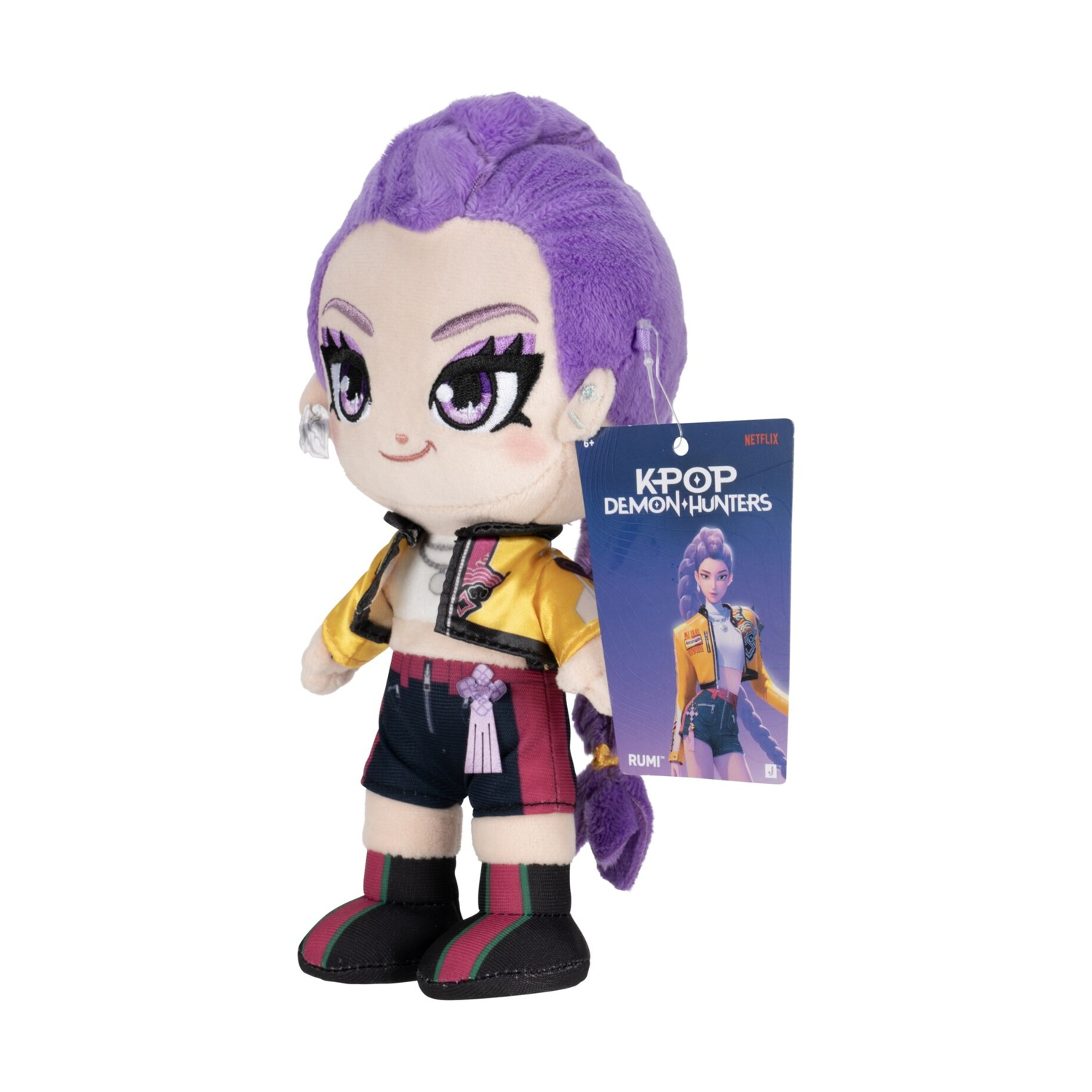 Un peluche con capelli viola, giacca gialla e pantaloncini neri, con un'etichetta K-Pop Demon Hunters.