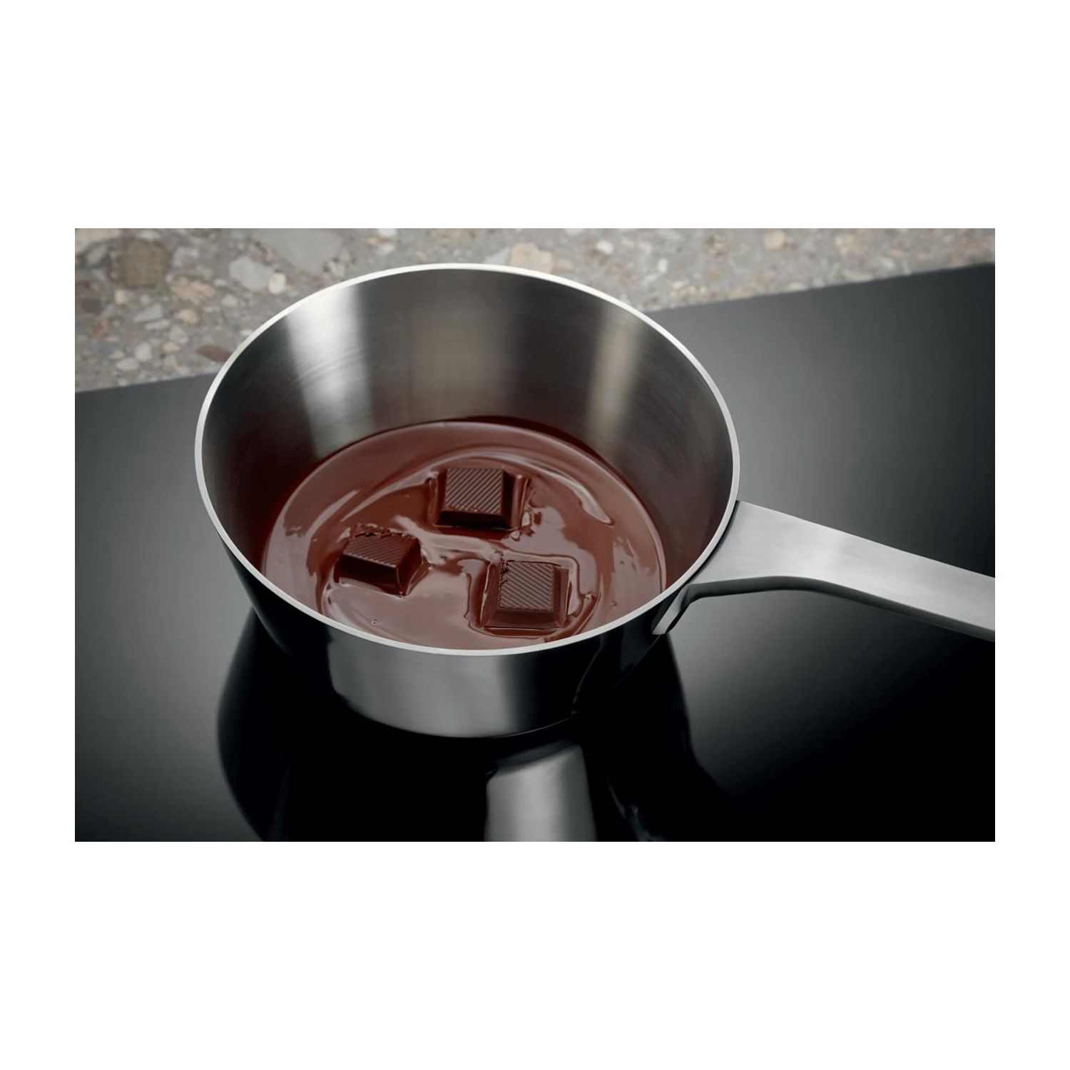 Pentola in acciaio inossidabile con cioccolato che si scioglie su un piano cottura.