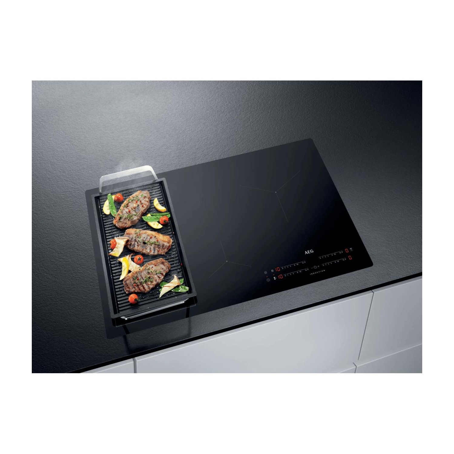 Piano cottura a induzione nero AEG con piastra grill su cui cuociono bistecche e verdure.