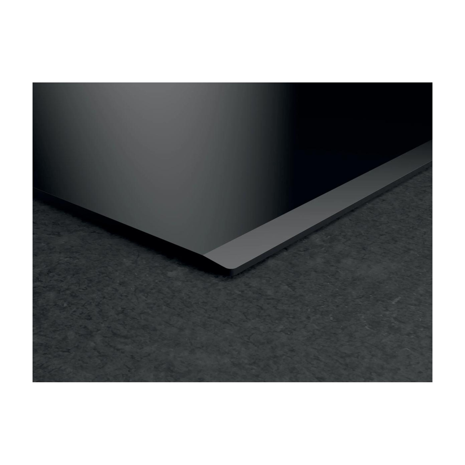 Piano cottura in vetroceramica nera con bordo smussato su piano di lavoro grigio.