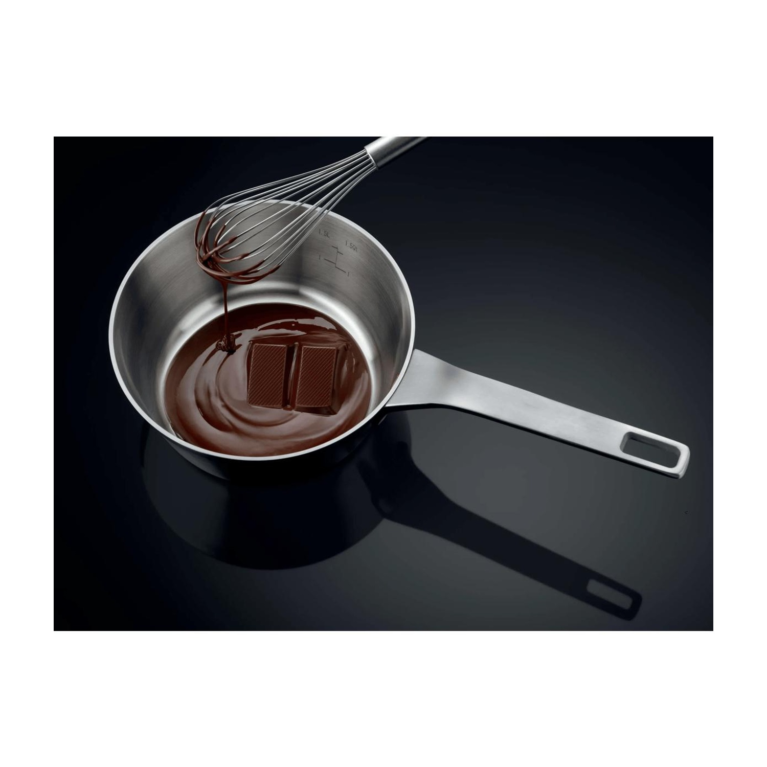 Il cioccolato si scioglie in una casseruola in acciaio inossidabile mentre una frusta lo mescola.