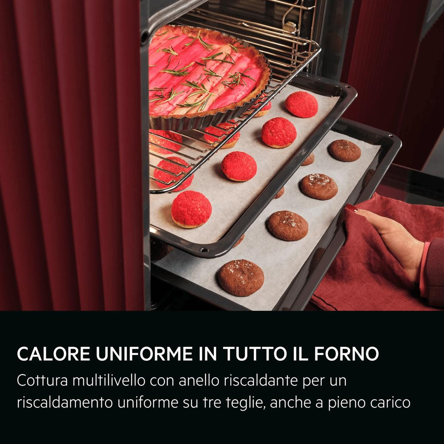 Un forno rosso cuoce una crostata, bignè rossi e biscotti su tre teglie.