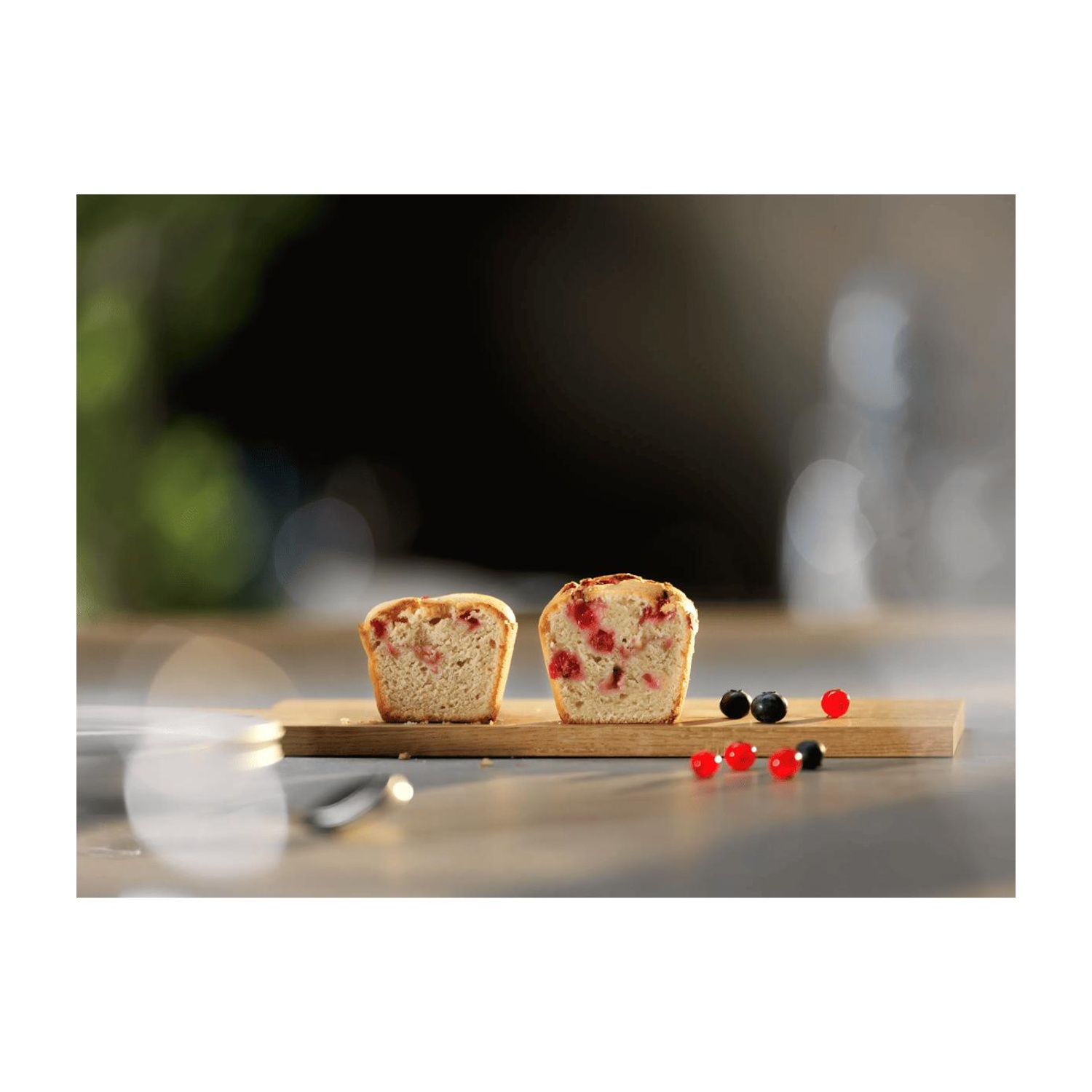 Due metà di una torta ai frutti rossi si trovano su un tagliere di legno.
