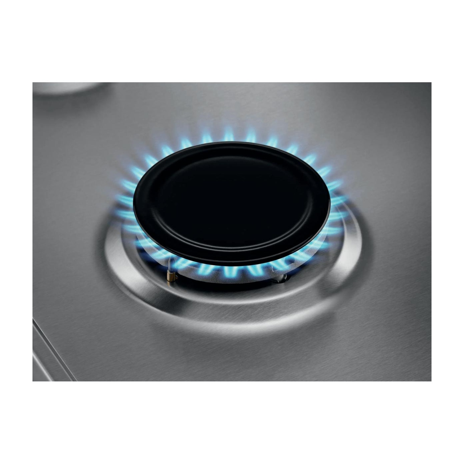 Un anello di fiamma di gas blu brucia sotto un coperchio bruciatore nero rotondo su un piano cottura in acciaio inox.