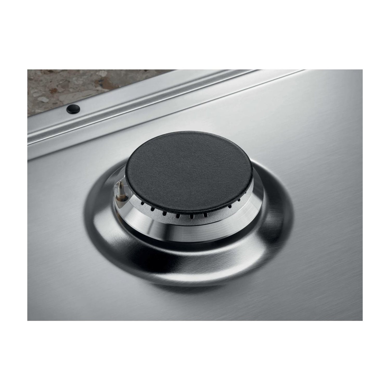 Bruciatore a gas in acciaio inox con cappuccio nero tondo su piano cottura metallico.