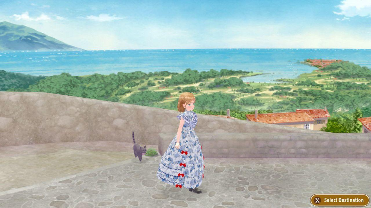 Eine Frau in einem blauen Kleid steht mit einer Katze auf einer Terrasse mit Blick auf das Meer.