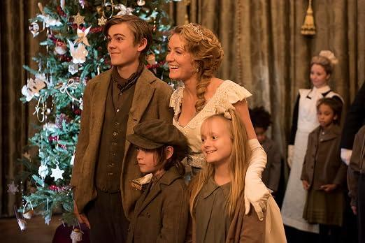 Eine Familie in historischer Kleidung posiert vor einem geschmückten Weihnachtsbaum mit weiteren Personen im Hintergrund.