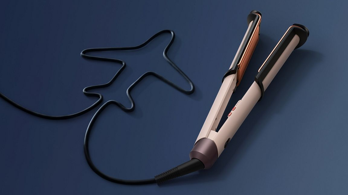 Ein beiges Glätteisen mit Kupferakzenten und einem Kabel, das wie ein Flugzeug geformt ist, vor blauem Hintergrund.