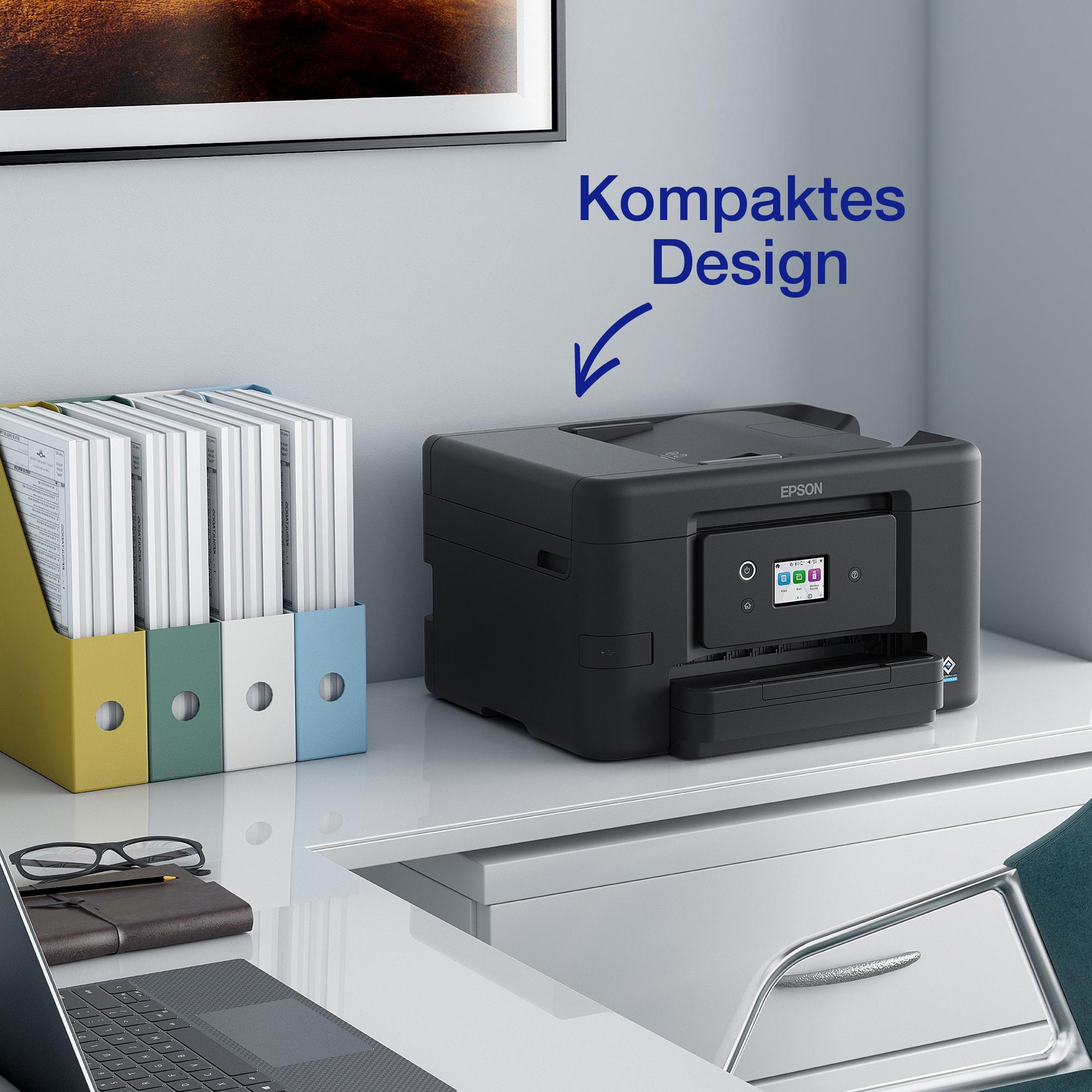 Ein schwarzer Epson-Drucker auf einem Schreibtisch neben bunten Dokumentenboxen, Brillen und einem Notizbuch.