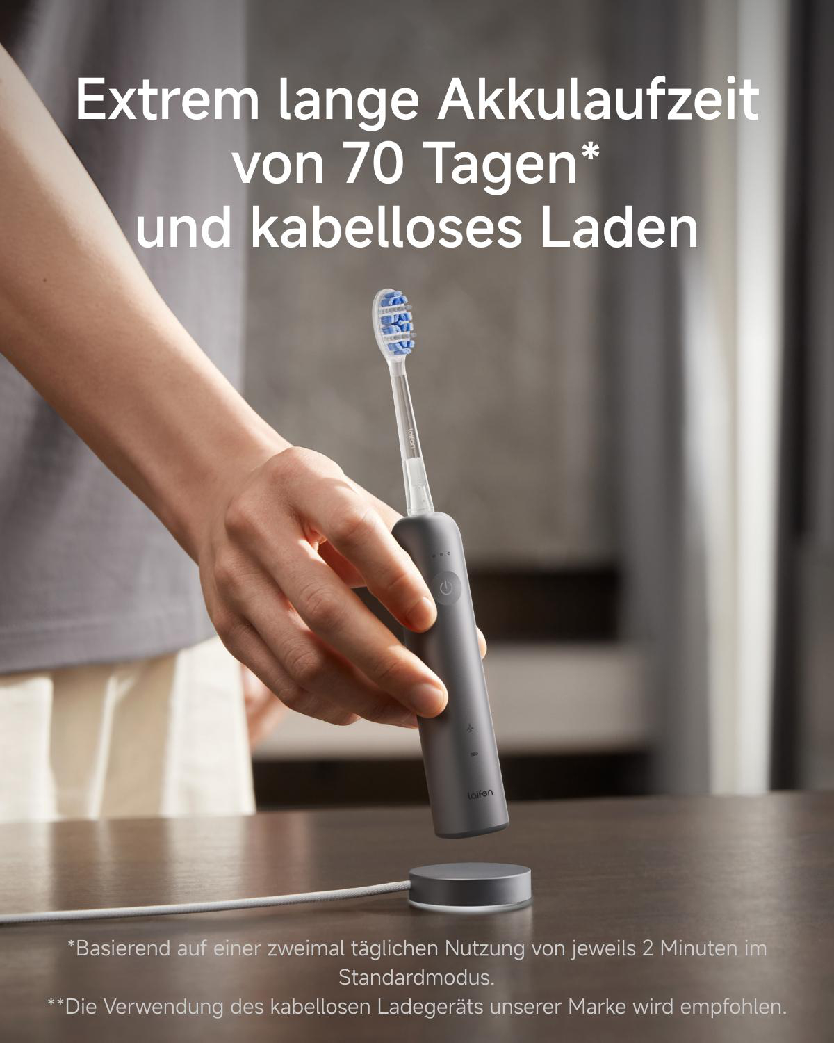 Eine Hand hält eine graue elektrische Zahnbürste über eine kabellose Ladestation.
