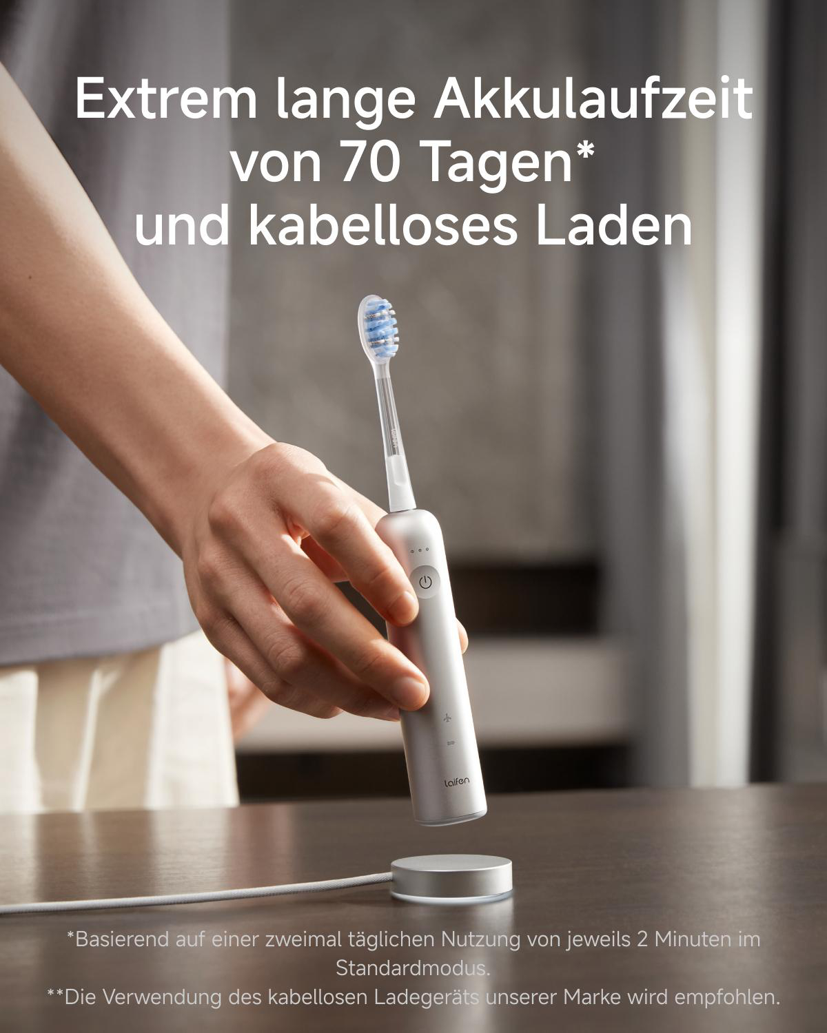 Eine Hand hält eine silberne elektrische Zahnbürste über ein kabelloses Ladegerät. Text oben und unten.