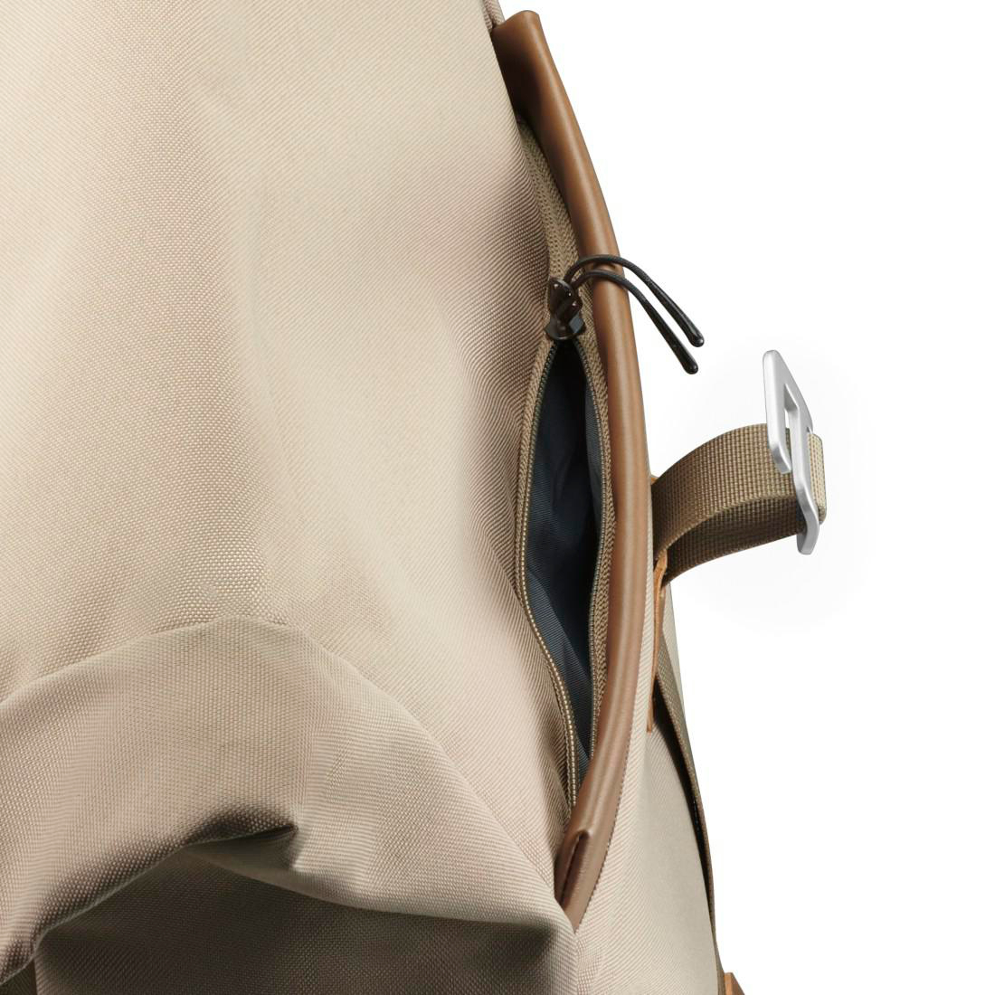 Nahaufnahme eines beigen Rucksacks mit Reißverschlusstasche und braunem Riemen mit Silberschnalle.