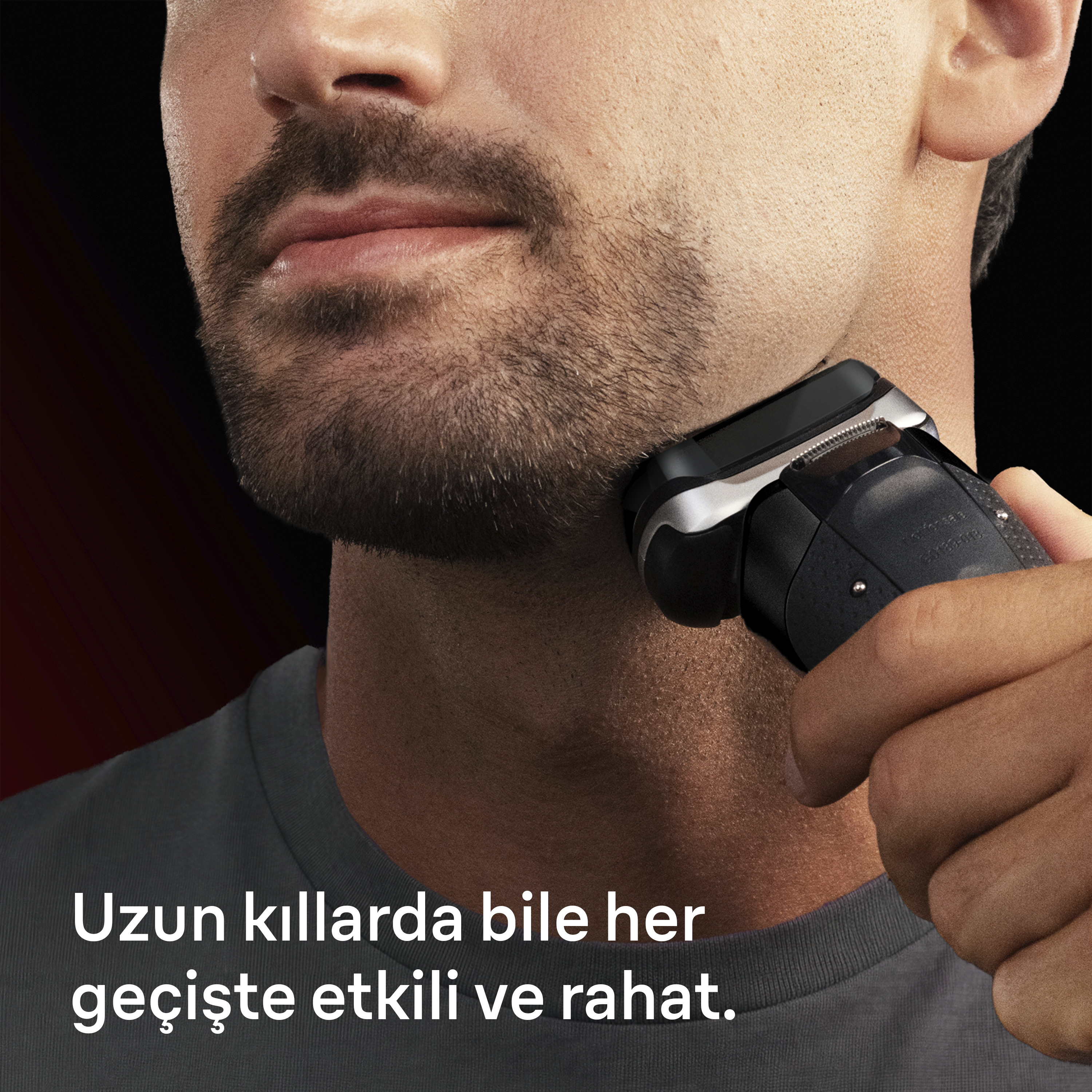 Bir adam elektrikli tıraş makinesiyle yüzünü tıraş ediyor.
