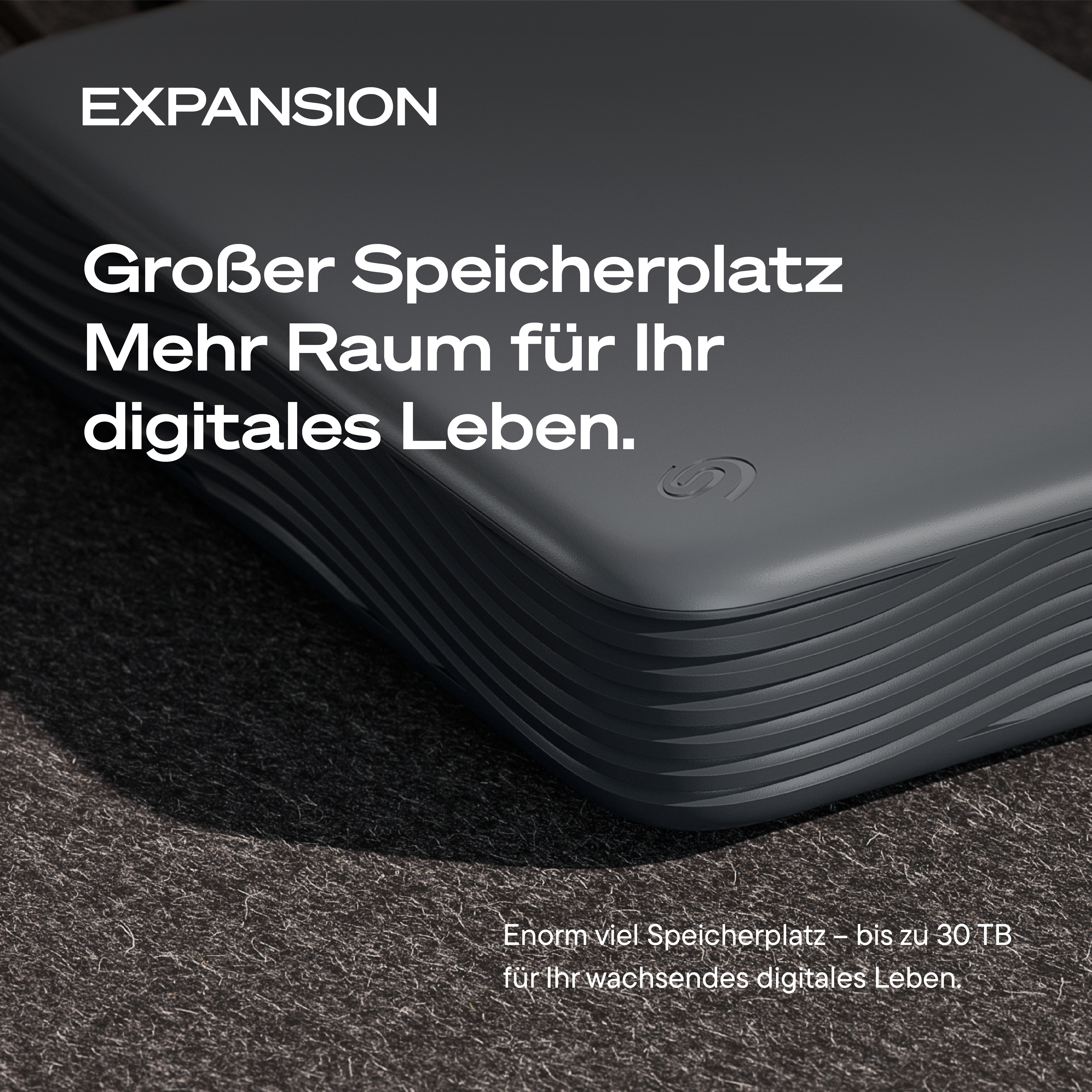 Graue Seagate Expansion Festplatte auf dunkler Oberfläche mit Werbetext.