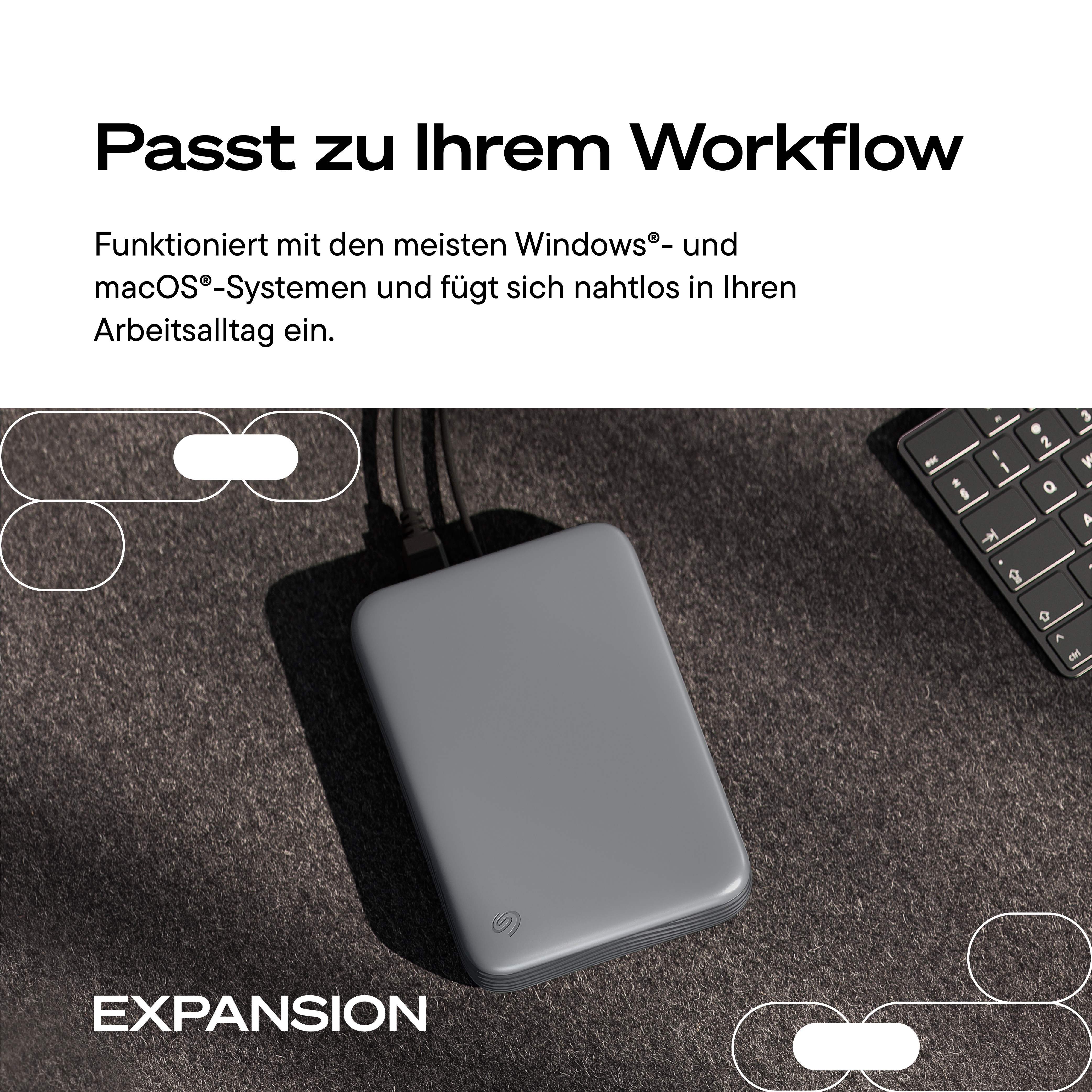 Graue Seagate Expansion Festplatte auf dunkler Oberfläche mit Text oben und unten.