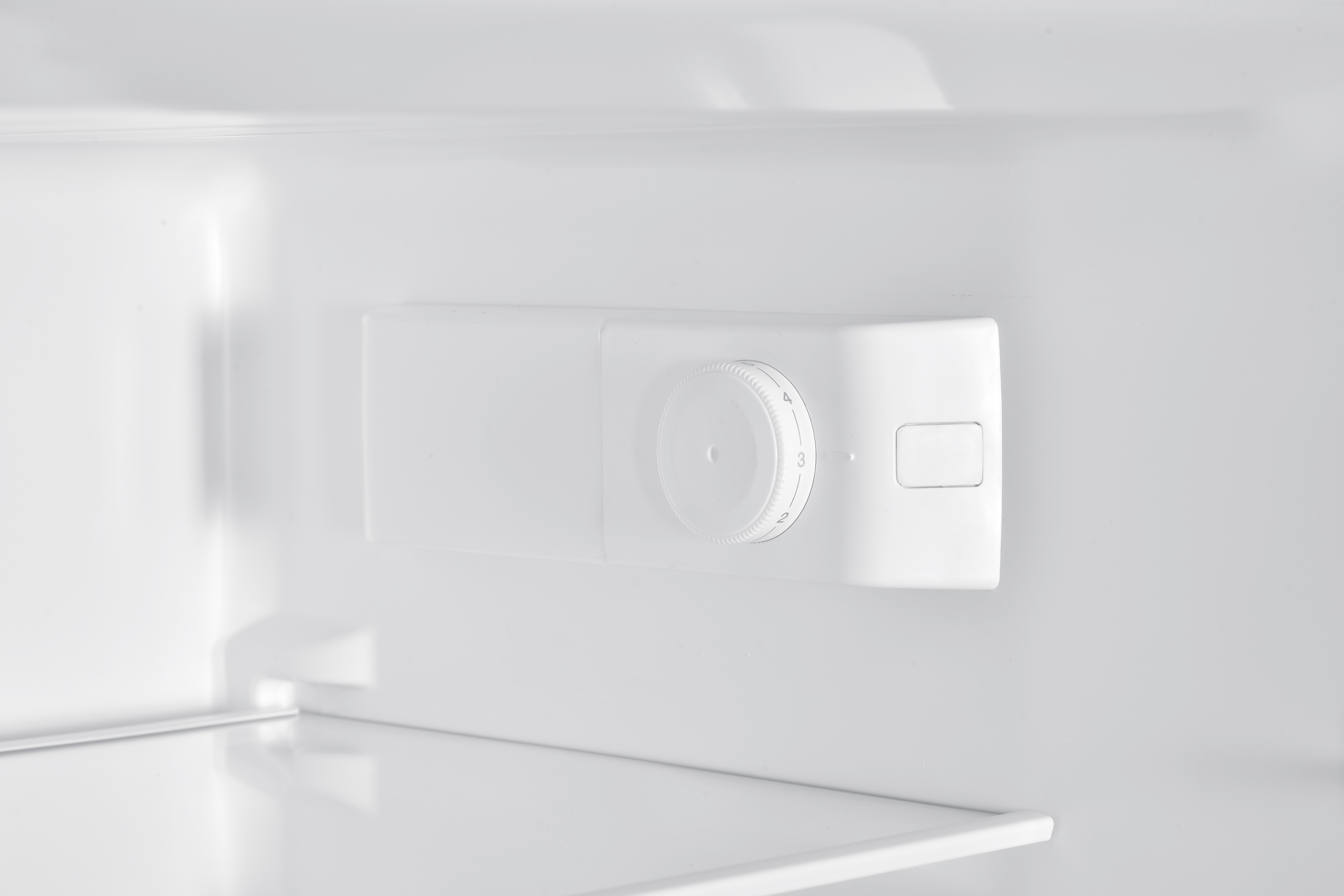 Weißer Kühlschrank-Temperaturregler mit Zahlenskala an der Innenwand.
