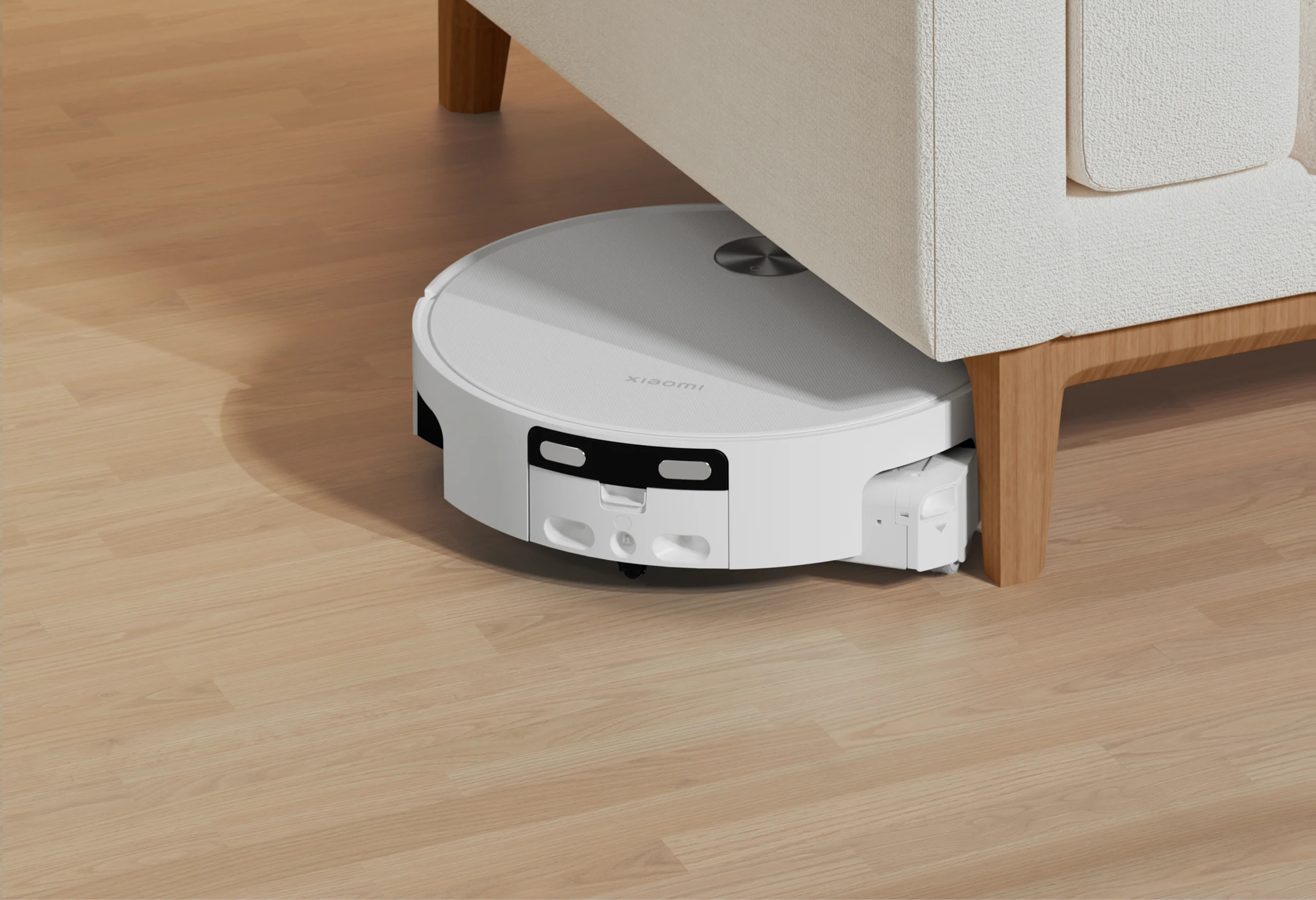 Biały odkurzacz automatyczny Xiaomi sprząta drewnianą podłogę pod kanapą.